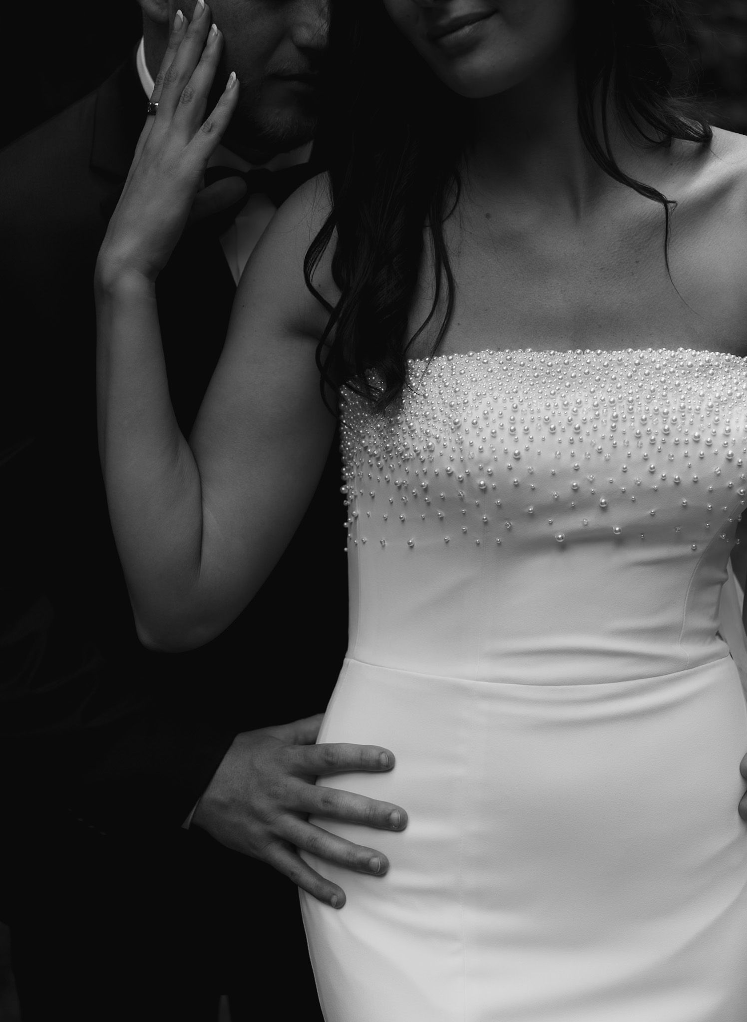 Close-up details of a white wedding dress with pearl beading.