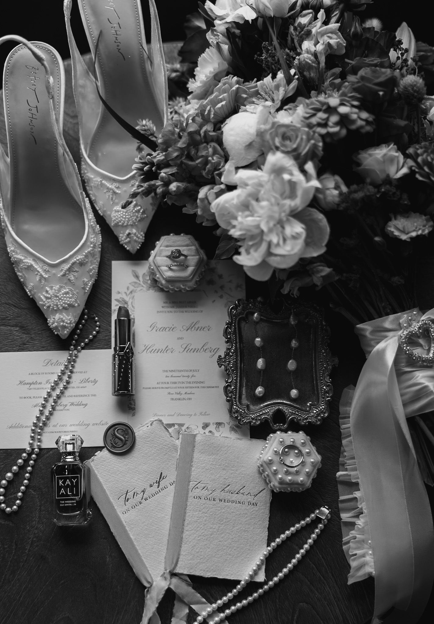 Wedding details including shoes, invitations, pearls and flowers arranged artistically.
