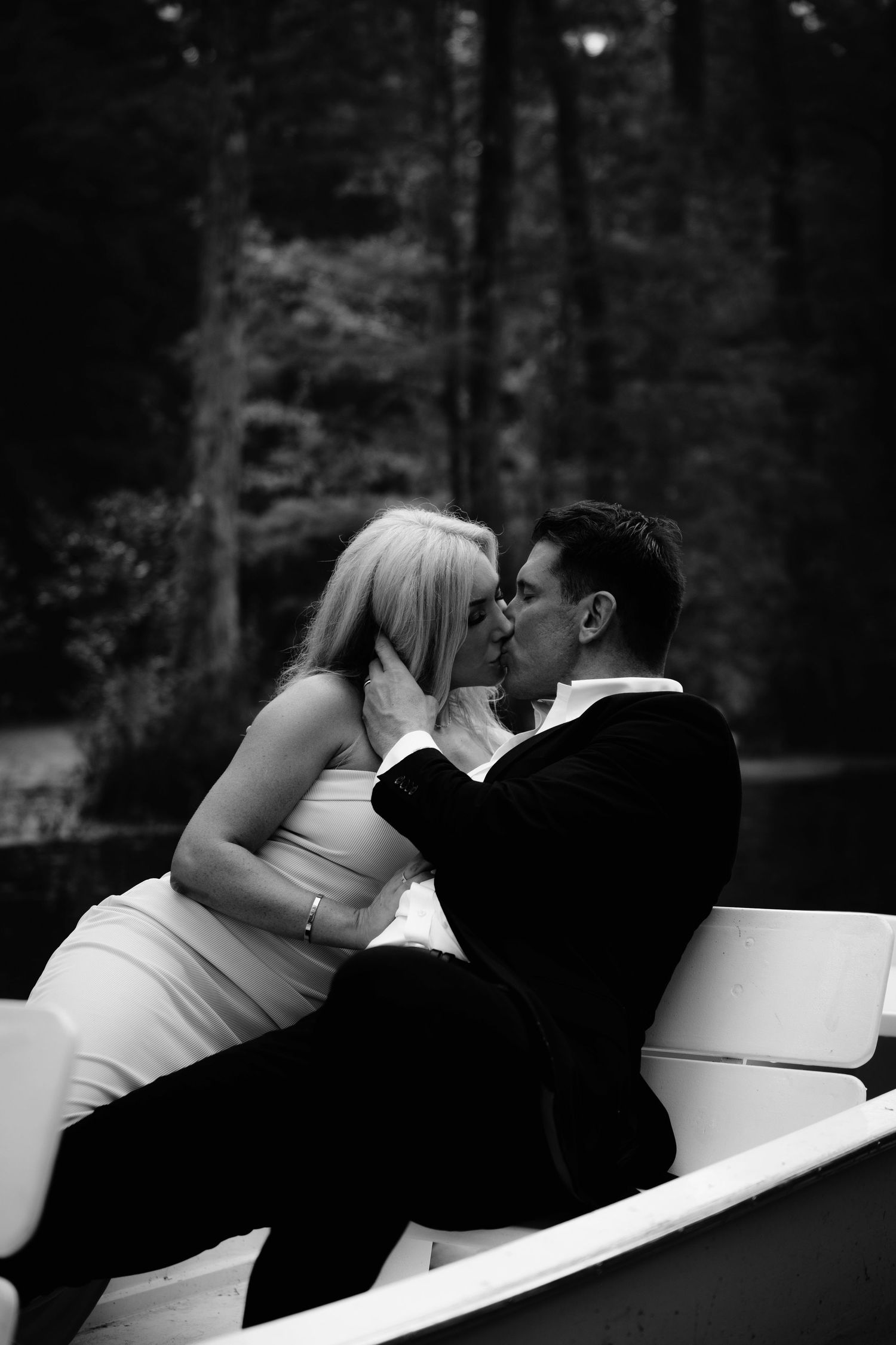 Romantic black and white photo of couple lounging on white outdoor furniture.