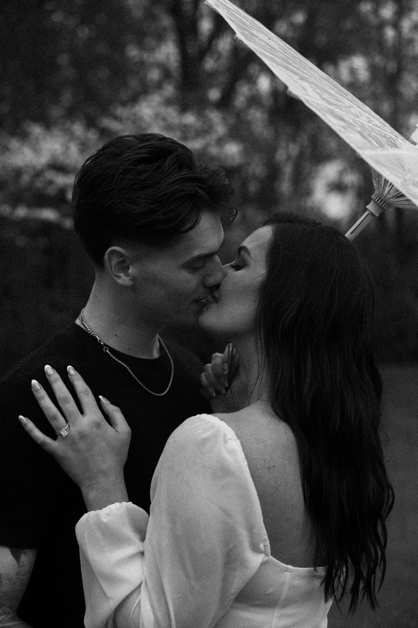 A romantic black and white sequence of a couple sharing an intimate kiss outdoors.