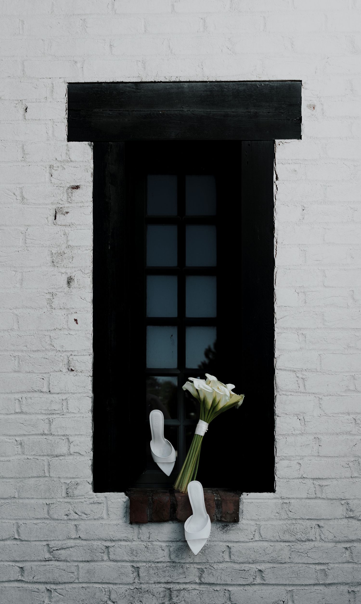 A series of black windows on a white brick wall with white flowers visible in one frame.