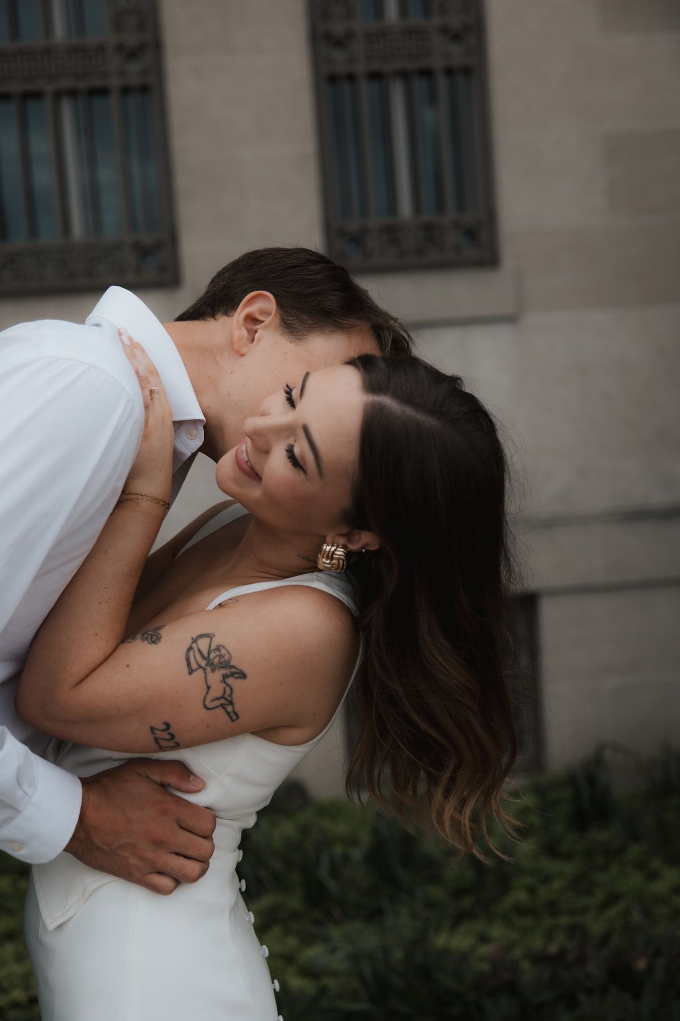 A tender embrace captured against a stone building exterior.