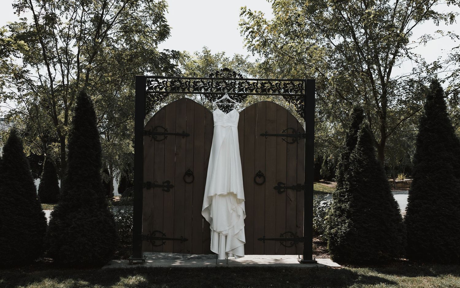 Wedding dress hanging outdoors against a backdrop of trees and natural scenery.