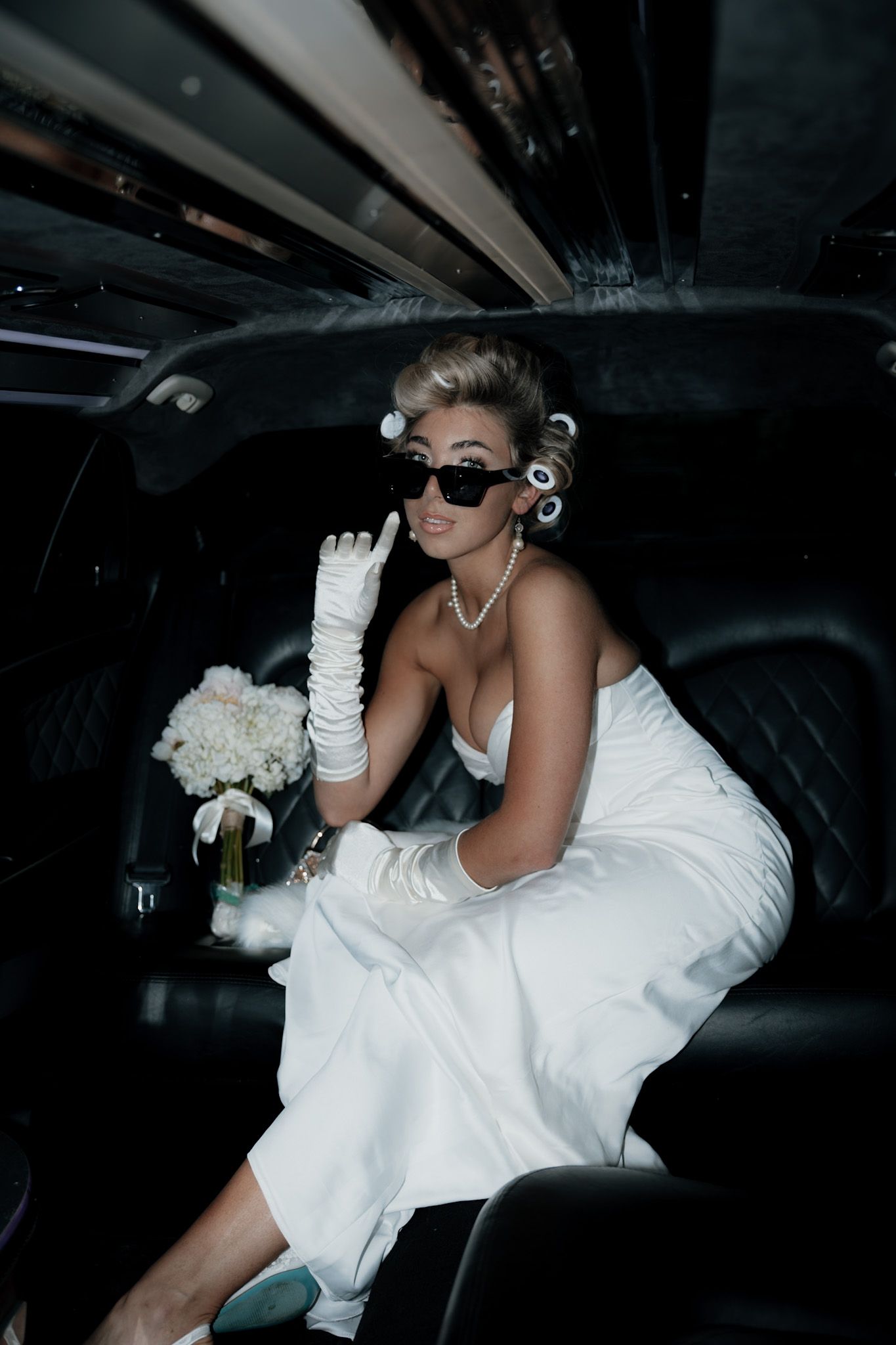 A glamorous bridal photo shoot in a limousine featuring elegant white gloves and a flowing dress.