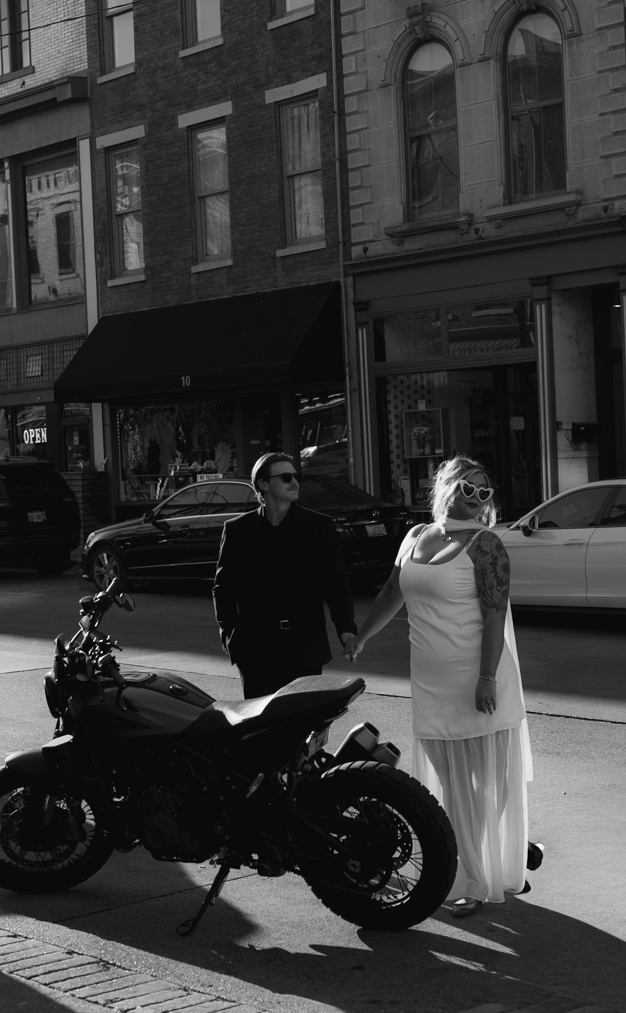 Wedding couple posing with motorcycles on an urban street.