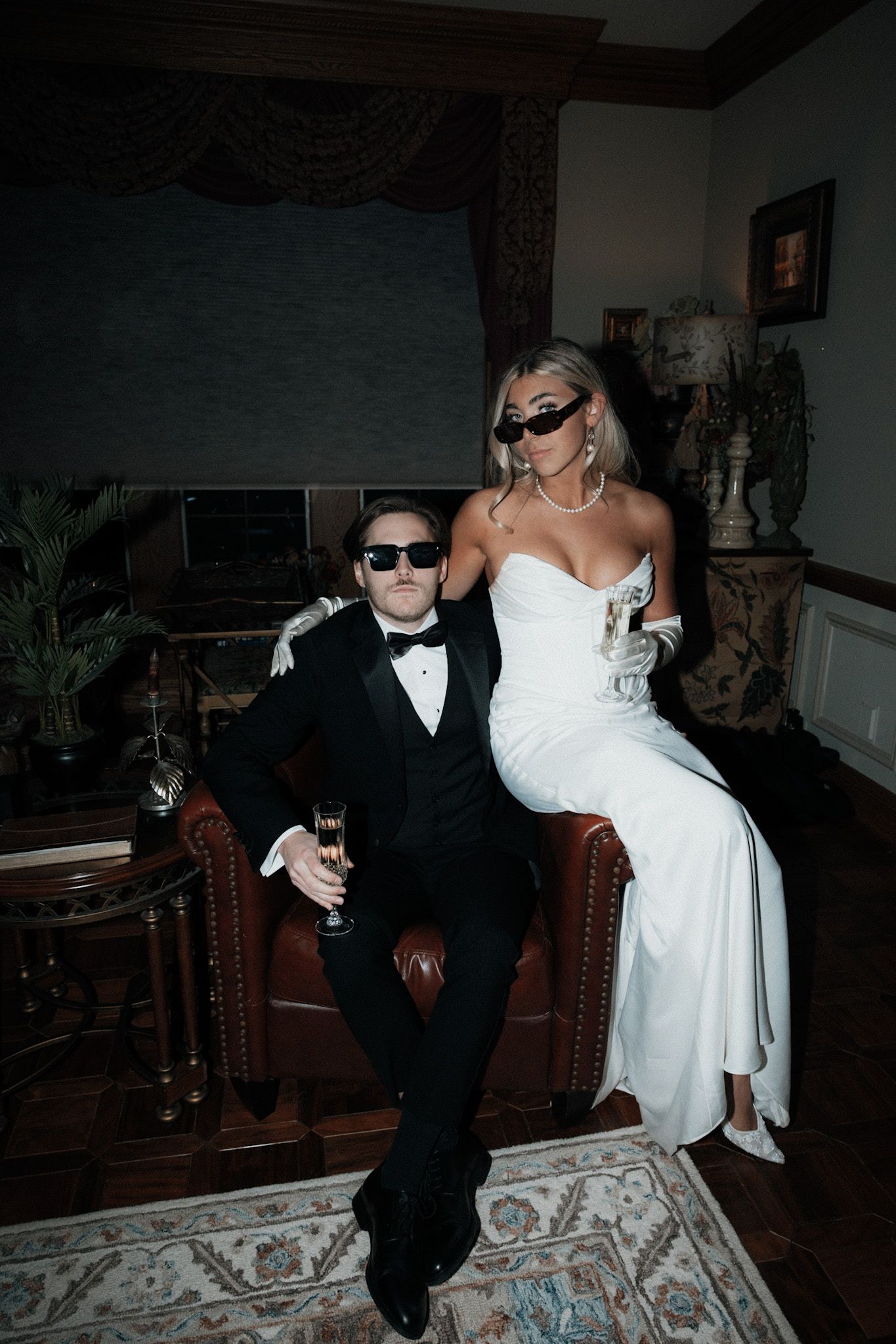 Wedding couple in sunglasses dancing playfully on patterned carpet.