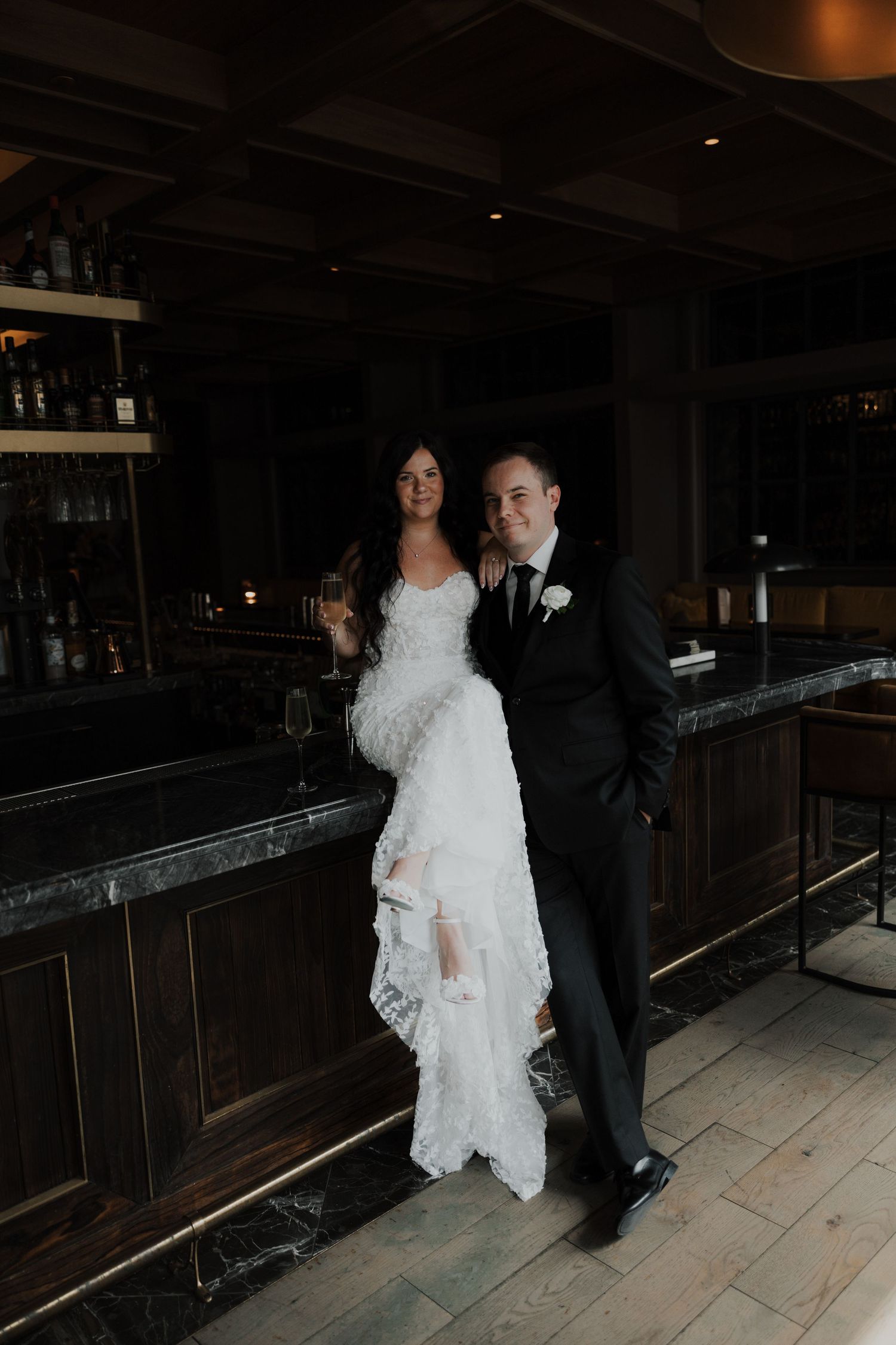 Couple dancing in a dimly lit venue with the bride wearing a flowing white lace dress.