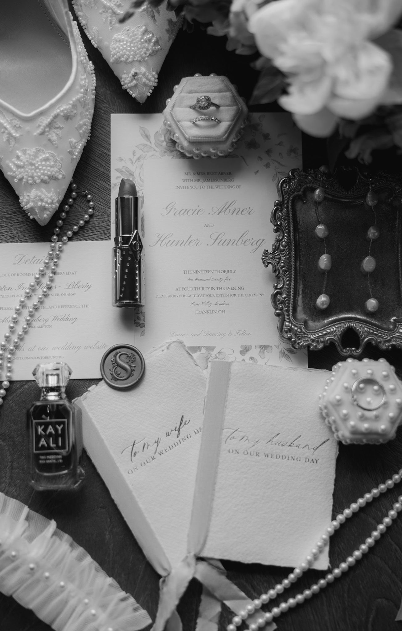 Wedding invitations and pearls arranged with decorative elements in black and white.