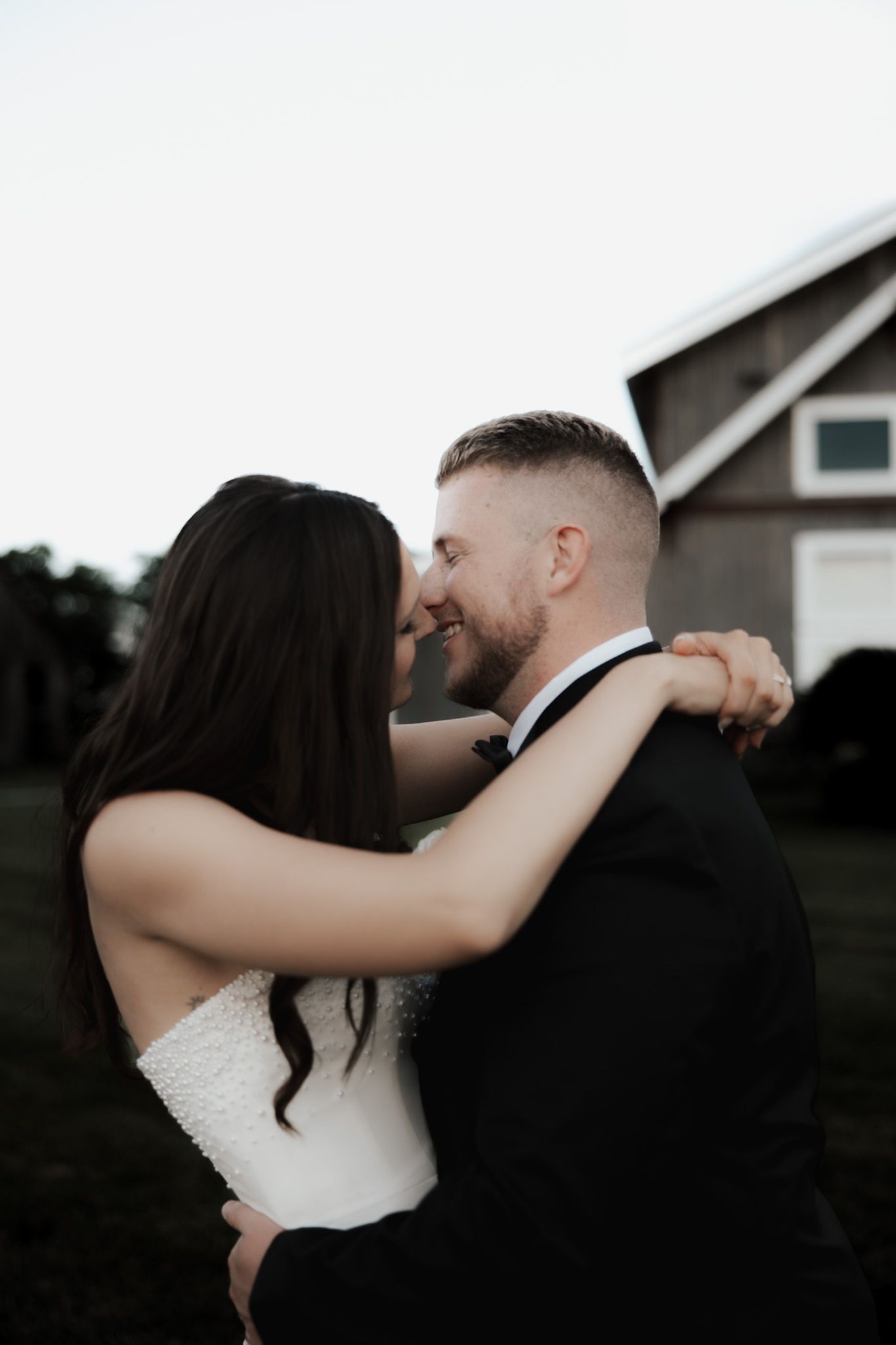 Romantic wedding portraits at dusk with a farmhouse in the background.