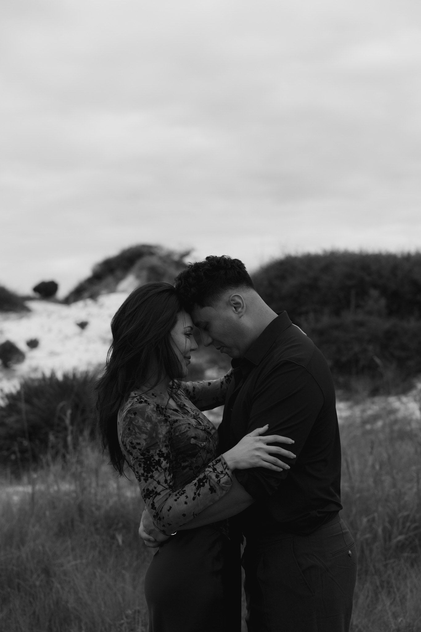 A romantic moment captured in black and white on a misty hillside.