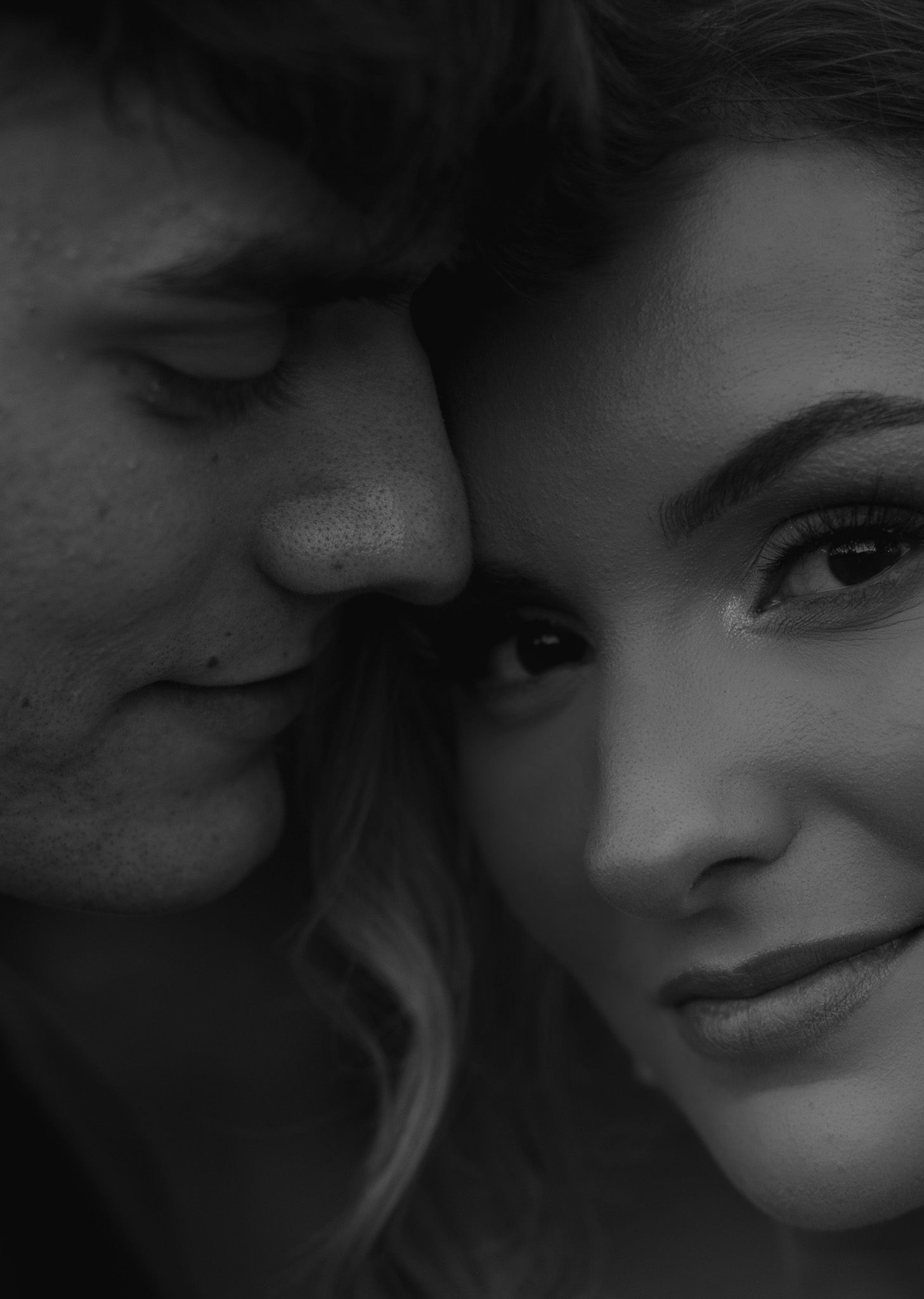An intimate black and white close-up portrait with dramatic lighting.