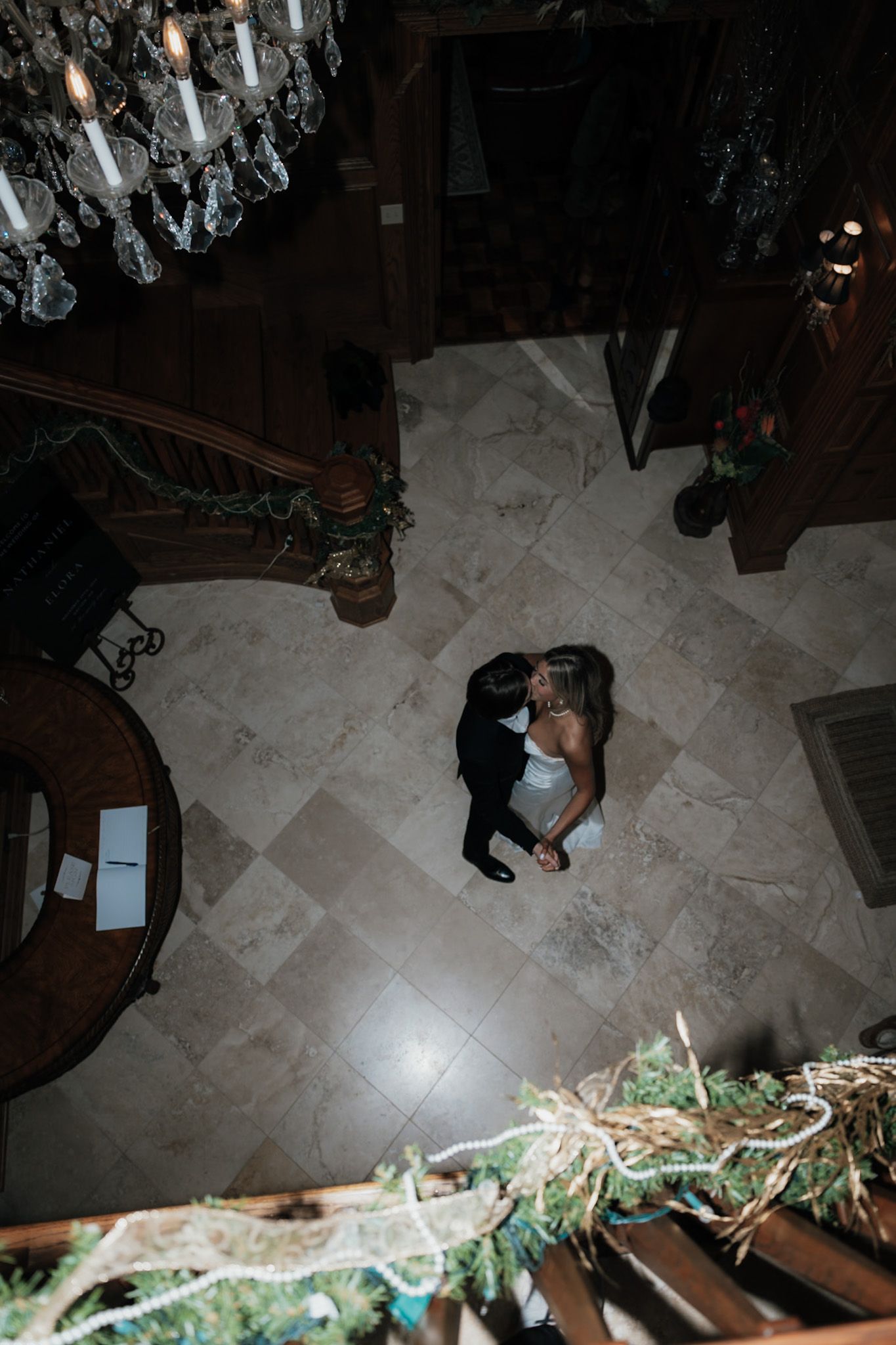 Dark reception venue with tiled floor and decorative greenery visible.