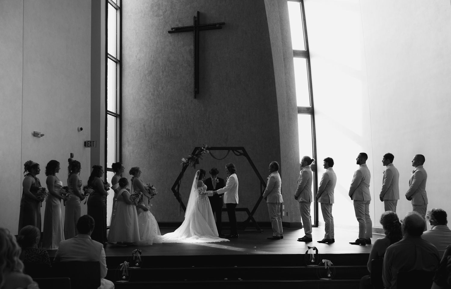 A church interior with rows of pews and silhouettes of people standing.
