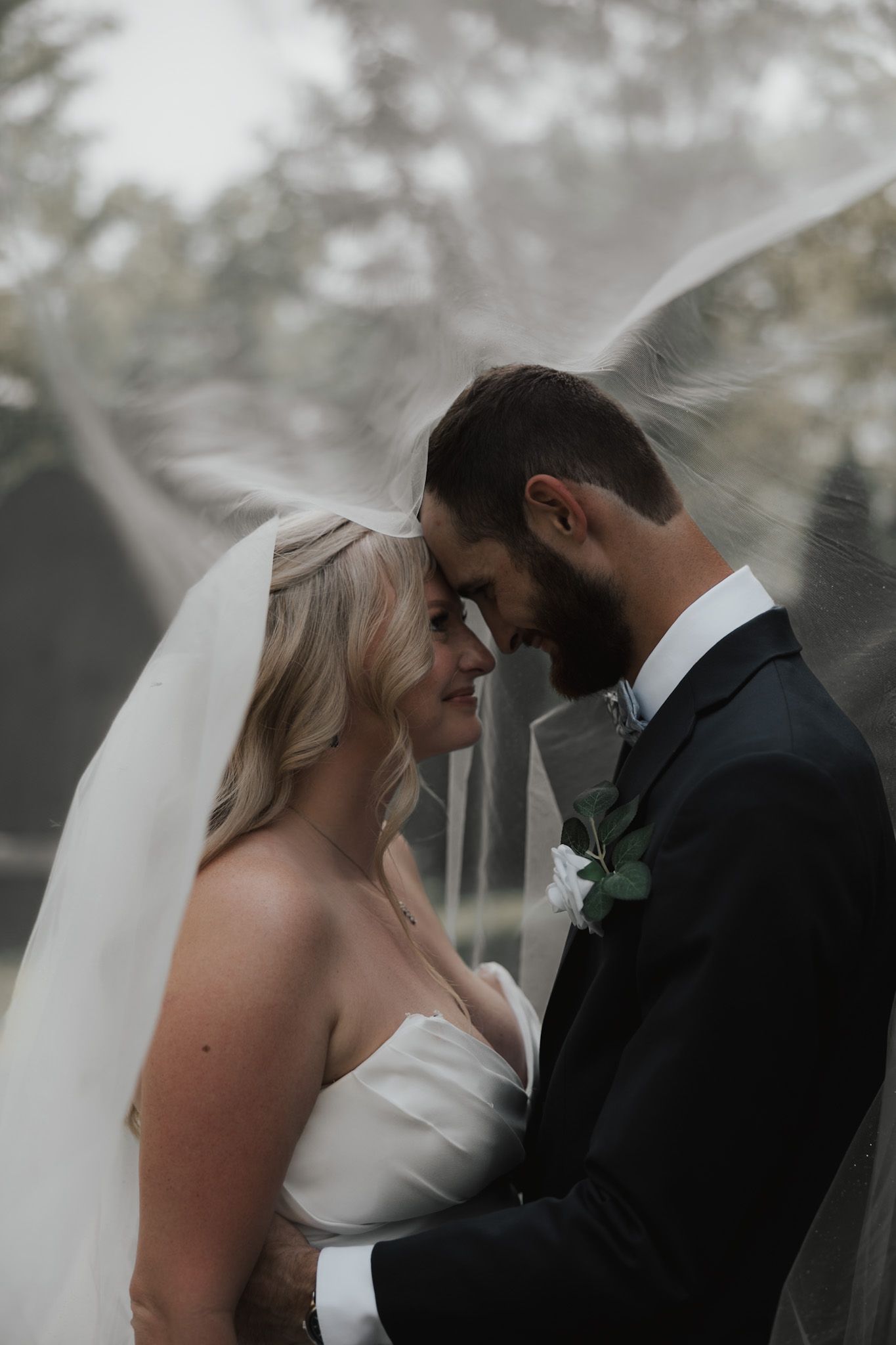 Atmospheric wedding portraits showing tender moments between newlyweds against a misty background.