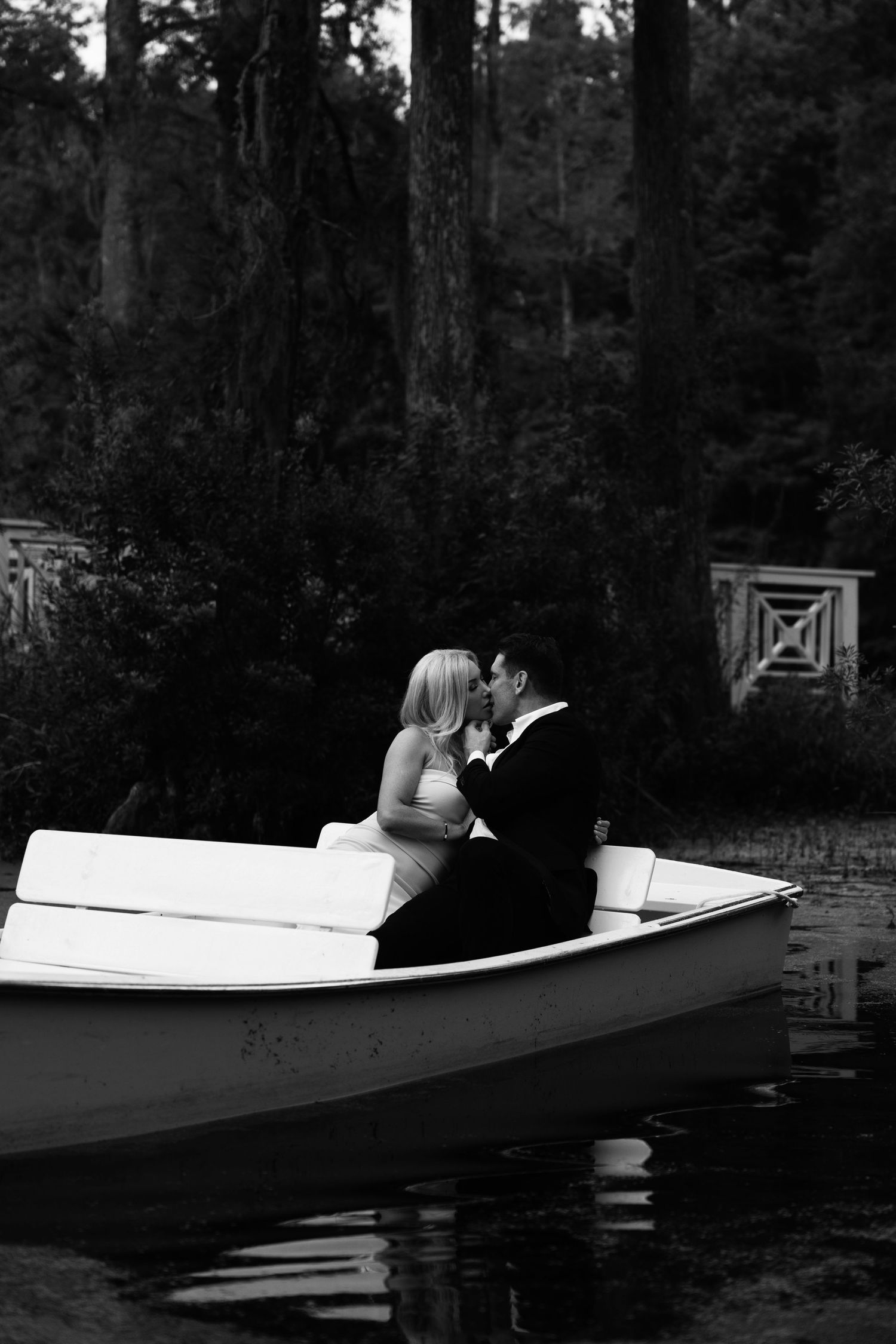 Black and white photos of couple in romantic boat scene surrounded by forest.