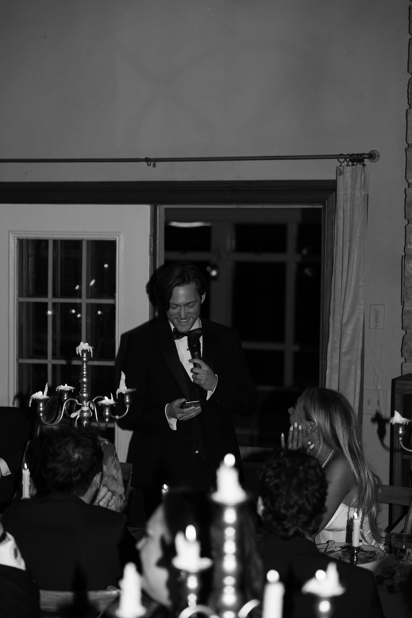 Candlelit wedding reception with guests seated at elegant dining tables.