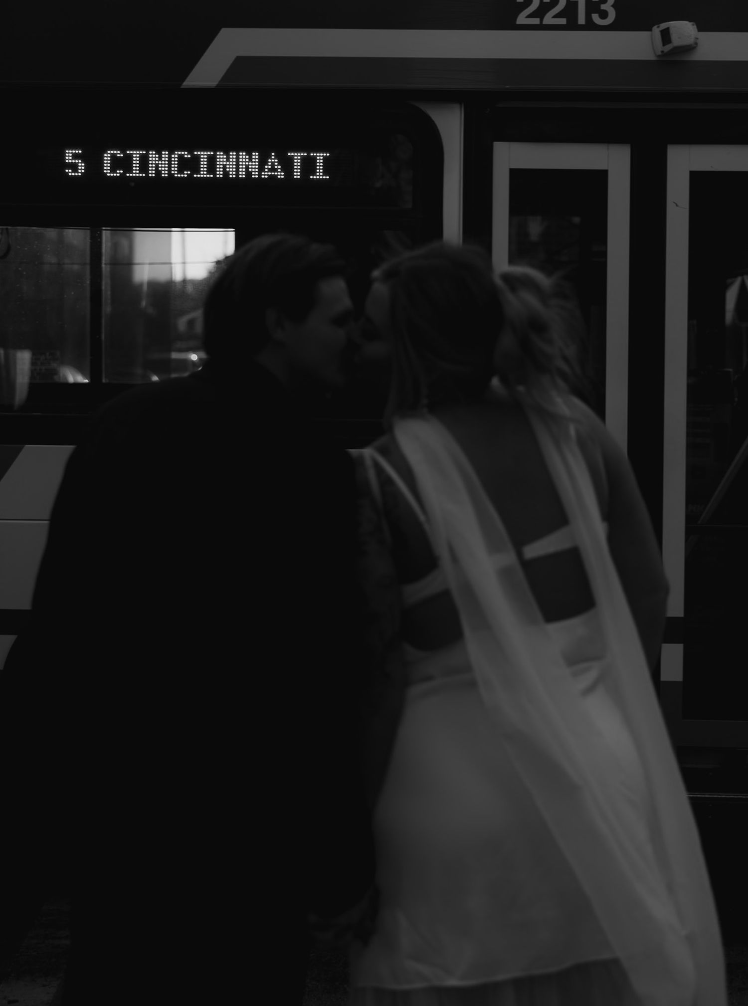 A silhouette of a bride in a veil against a dark urban background in Cincinnati.