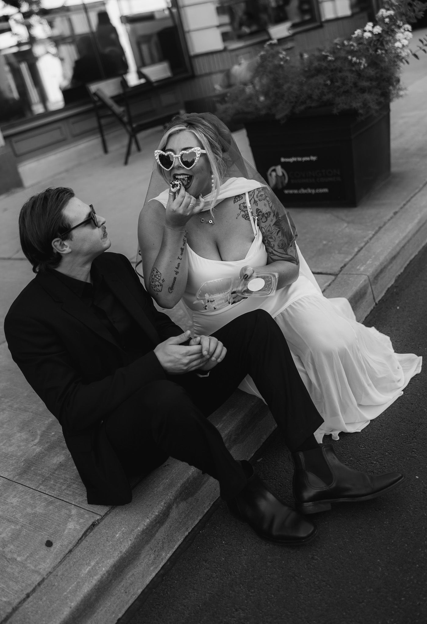 Playful black and white sequence of a couple sitting on a city sidewalk.