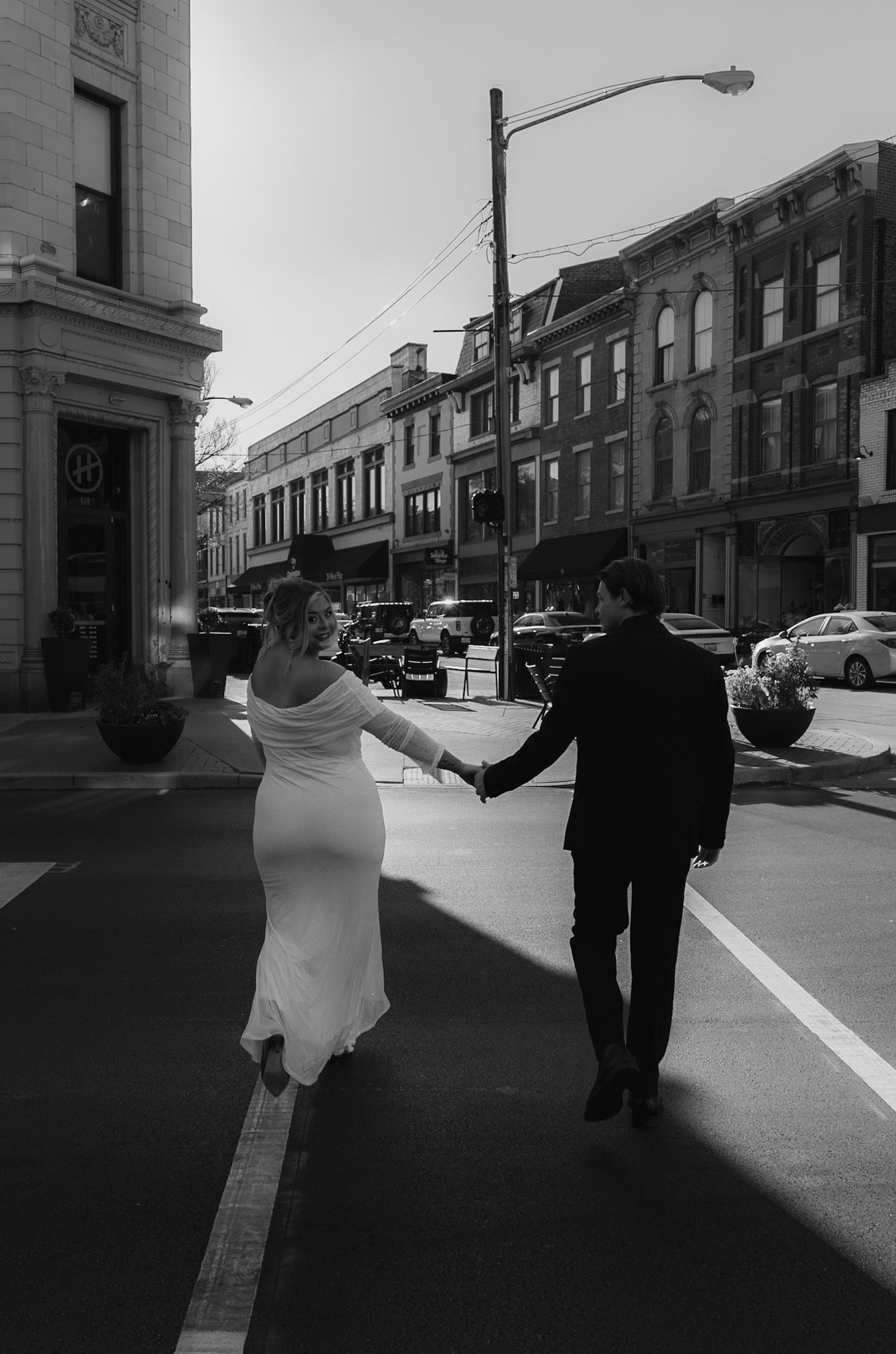 A black and white street scene shows a couple walking together in an urban setting.