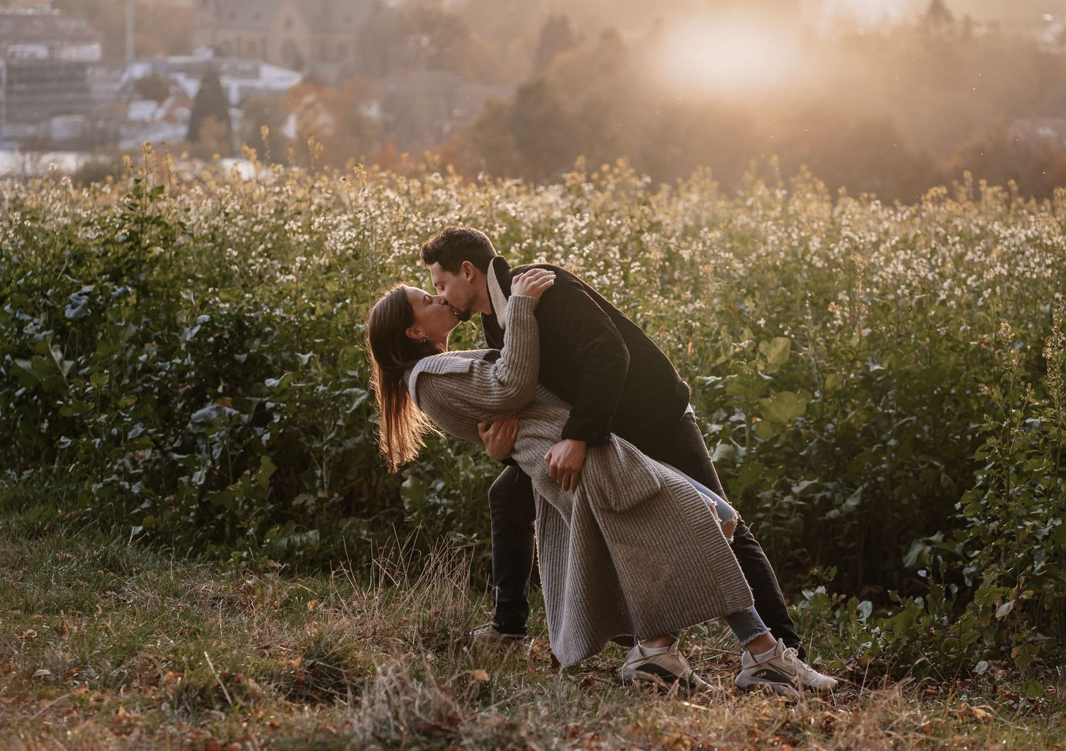 Couple sharing a romantic dip kiss in a sunlit wildflower field at golden hour. Couple Shooting.
