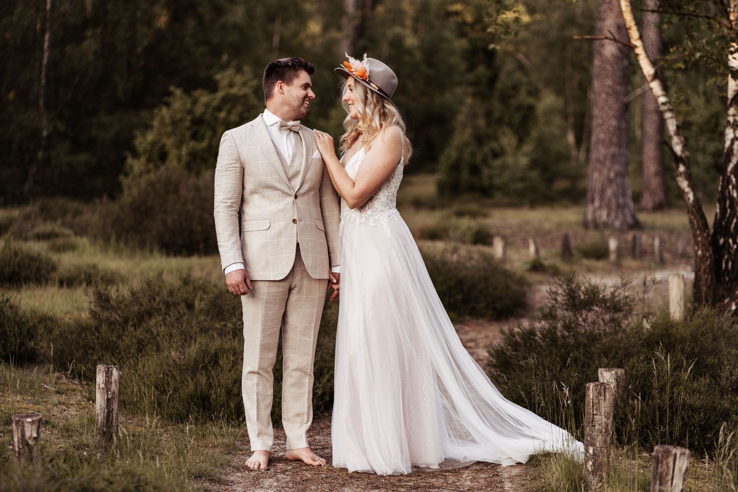 Eine Braut und ein Bräutigam teilen einen romantischen Moment auf einer Waldlichtung, gekleidet in ein elegantes weißes Kleid. Münster.