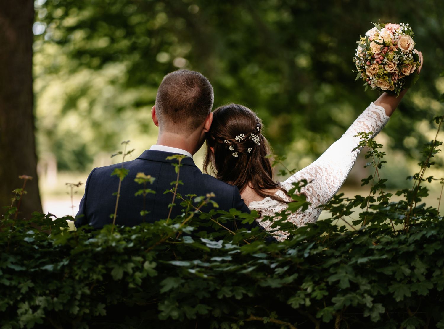 Hochzeiten Fotografie Münster - Ehepaar glücklich mit Strauß in der Luft