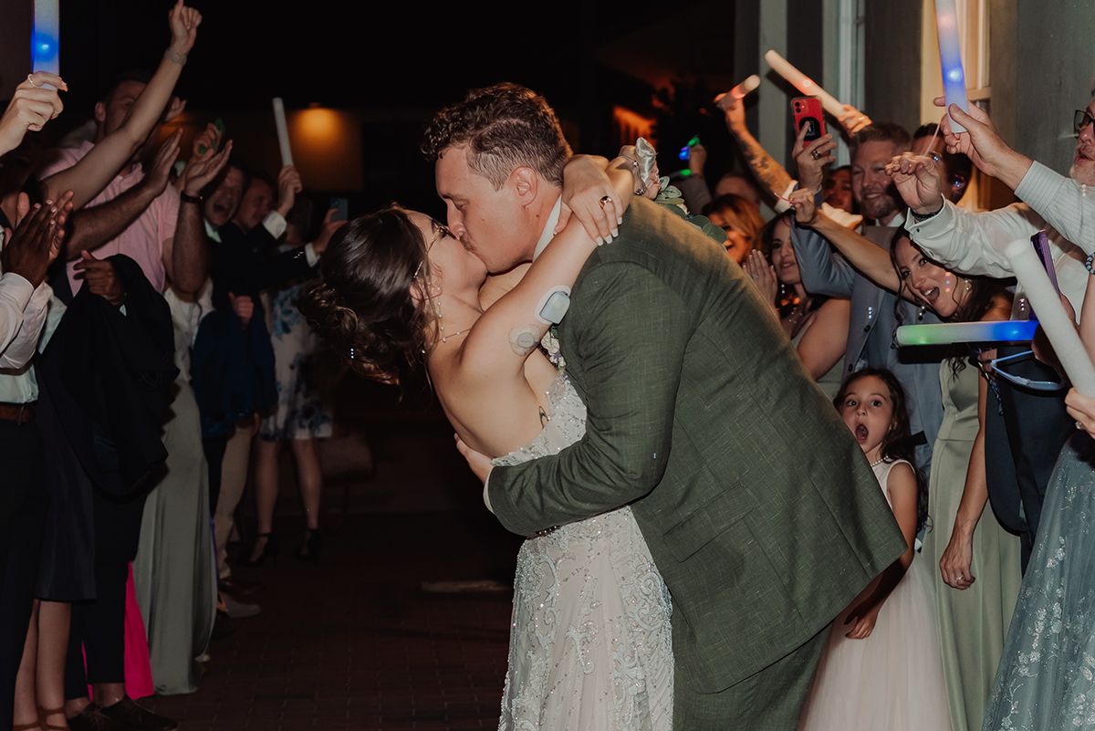 Wedding guests dance and celebrate on a dimly lit dance floor during a lively reception party.