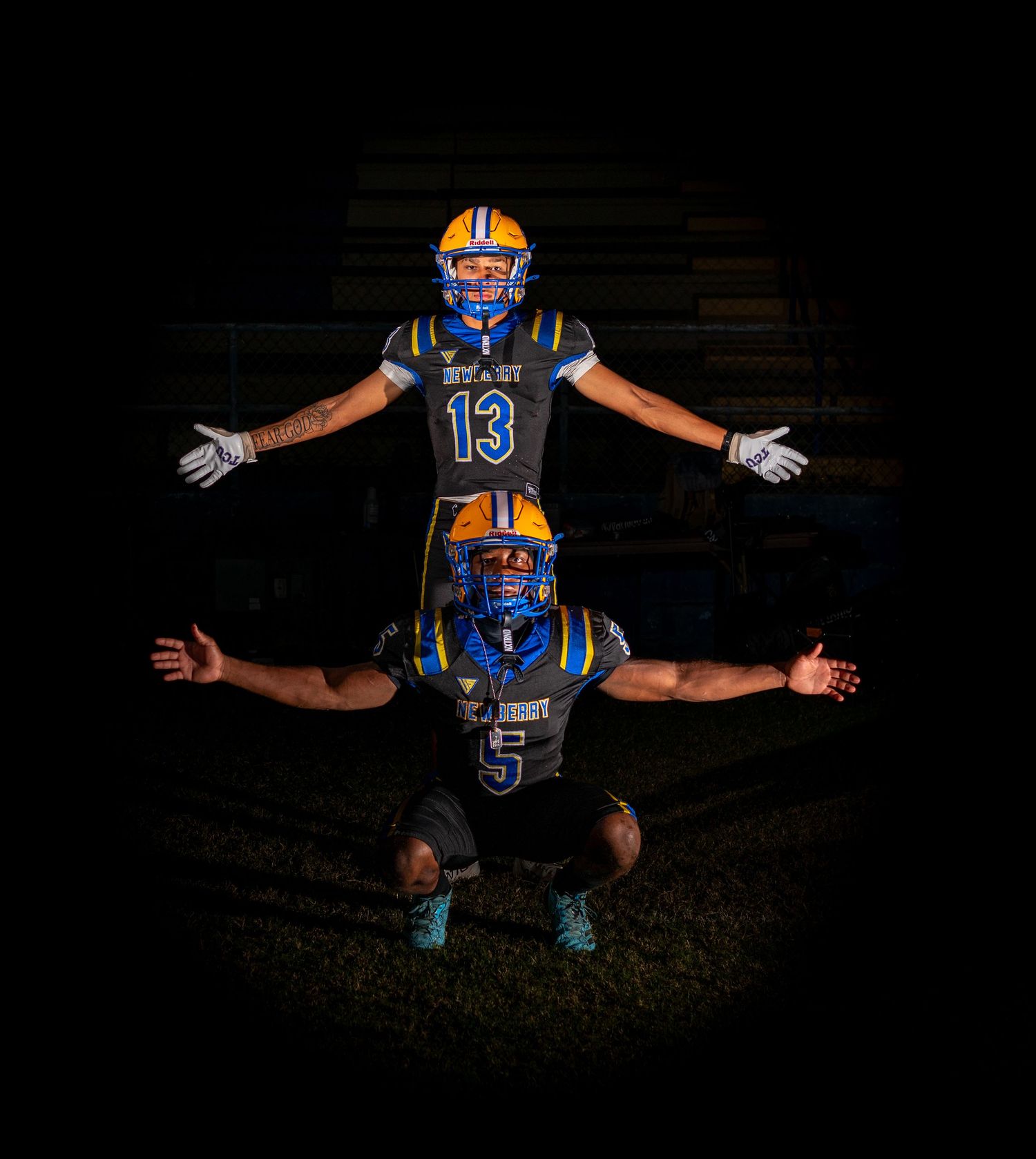 Football player in blue jersey and helmet poses for action shots at night against dark background for Newberry Panthers Football in Newberry