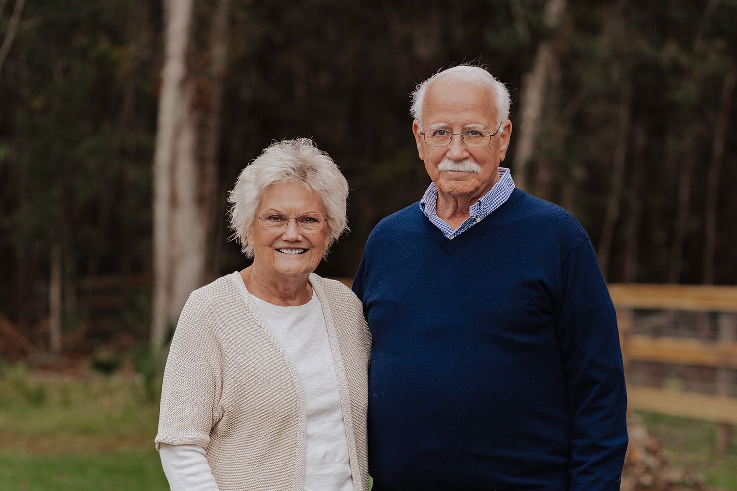 A couple in coordinated cream and navy outfits share a tender moment together outdoors for family photos in Gainesville Florida