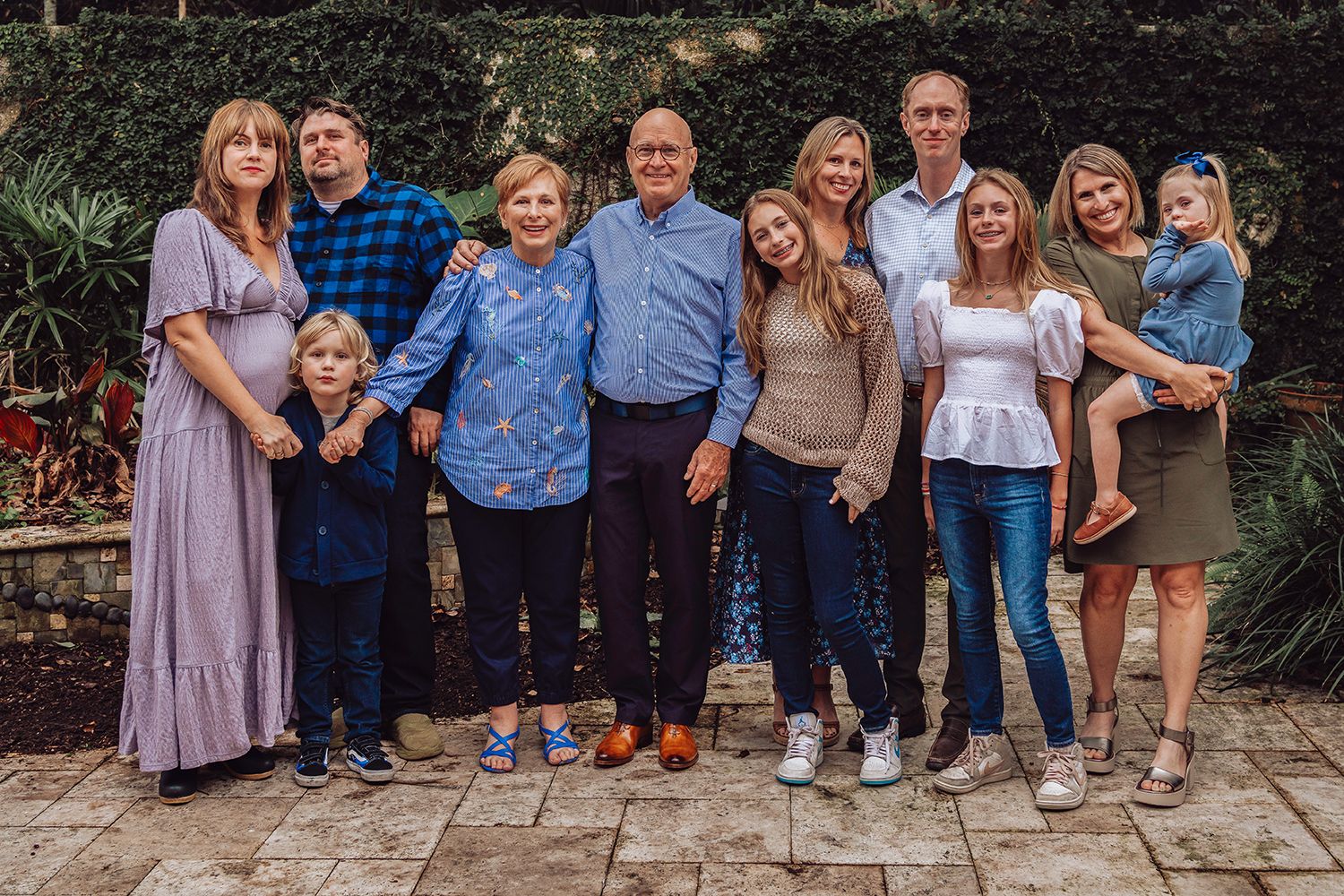 Outdoor family portraits with people wearing coordinated blue and neutral toned outfits in a garden setting in Jacksonville Florida