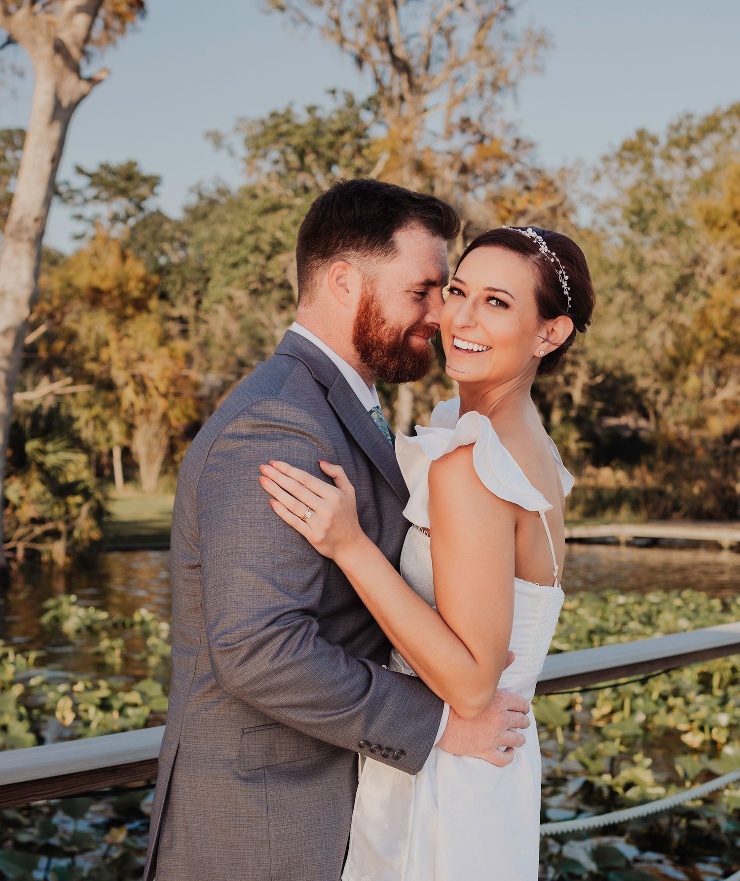 A romantic couple shares tender moments in a garden setting during golden hour with autumn trees in the background.