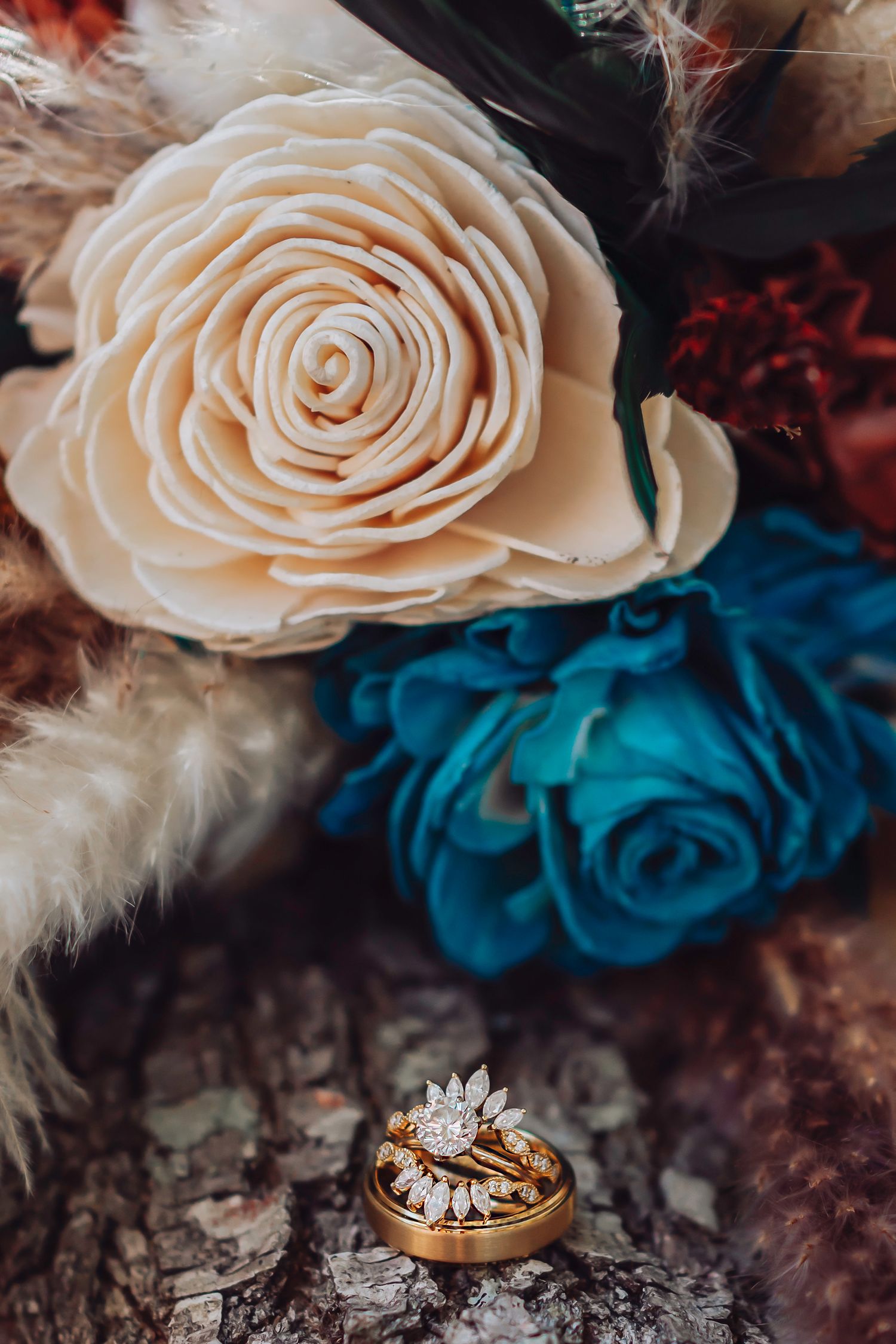 Wedding Details of Wedding rings displayed with cream and teal roses against log. Wedding photographer in Ocala, FL.