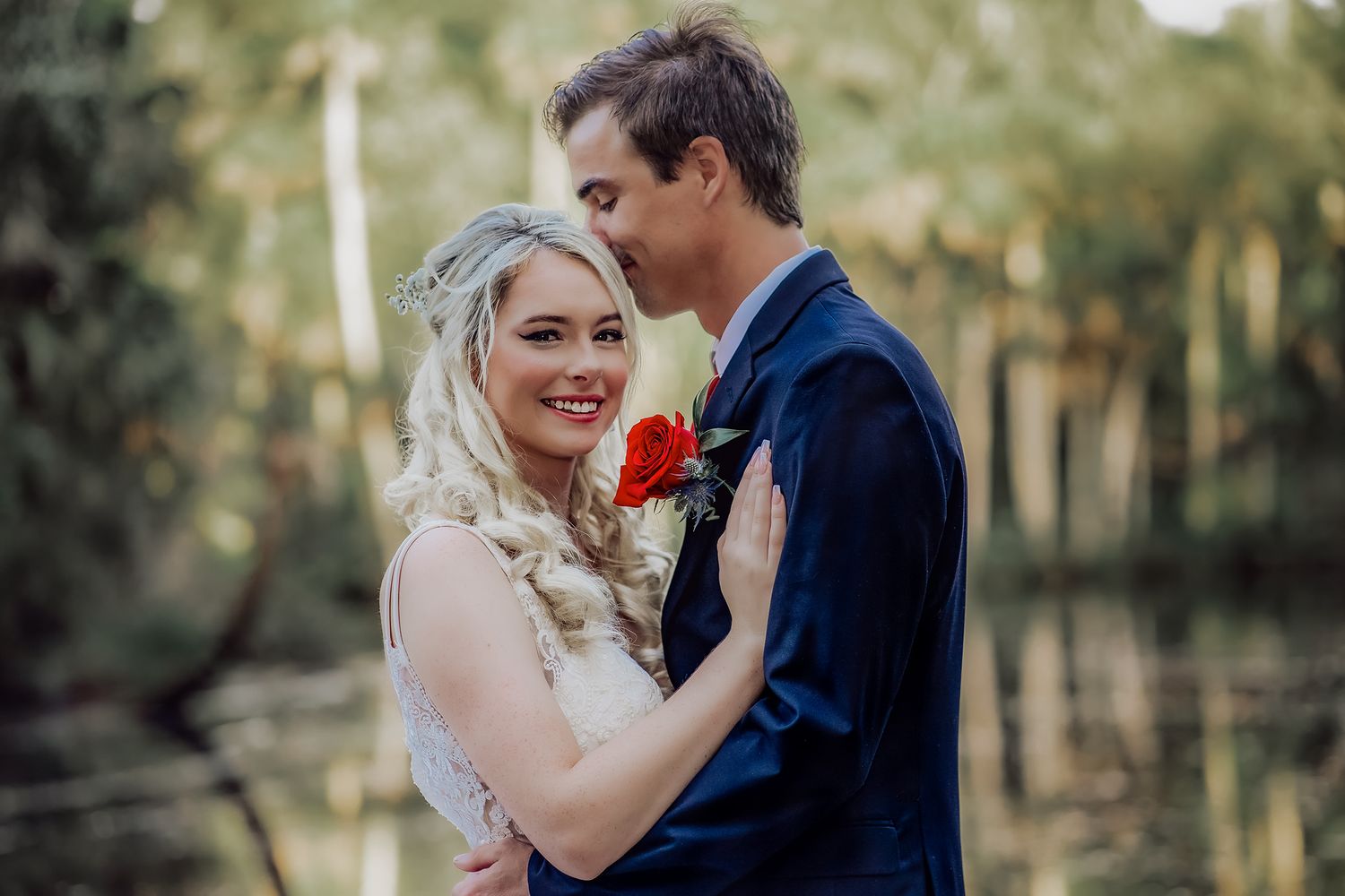 A couple shares an intimate moment during their wedding celebration in a lush outdoor setting.