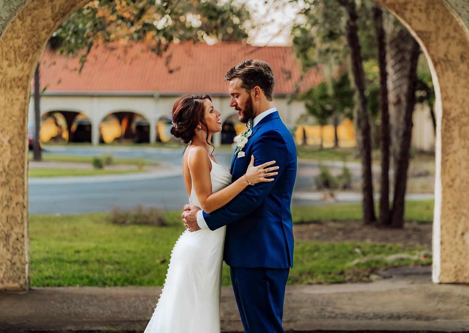 A couple in wedding attire dancing together under trees in a park setting during a romantic moment for wedding photography in Savannah, GA