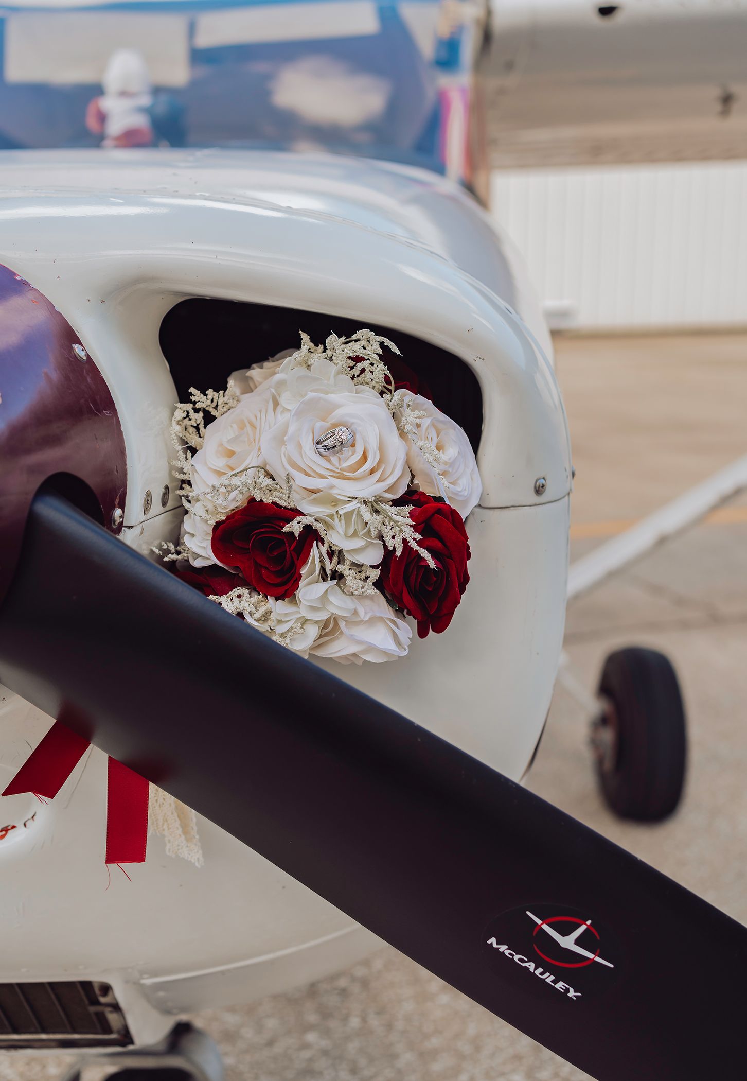 A white aircraft propeller with red and white roses elegantly arranged on its blade creates a romantic aviation scene.