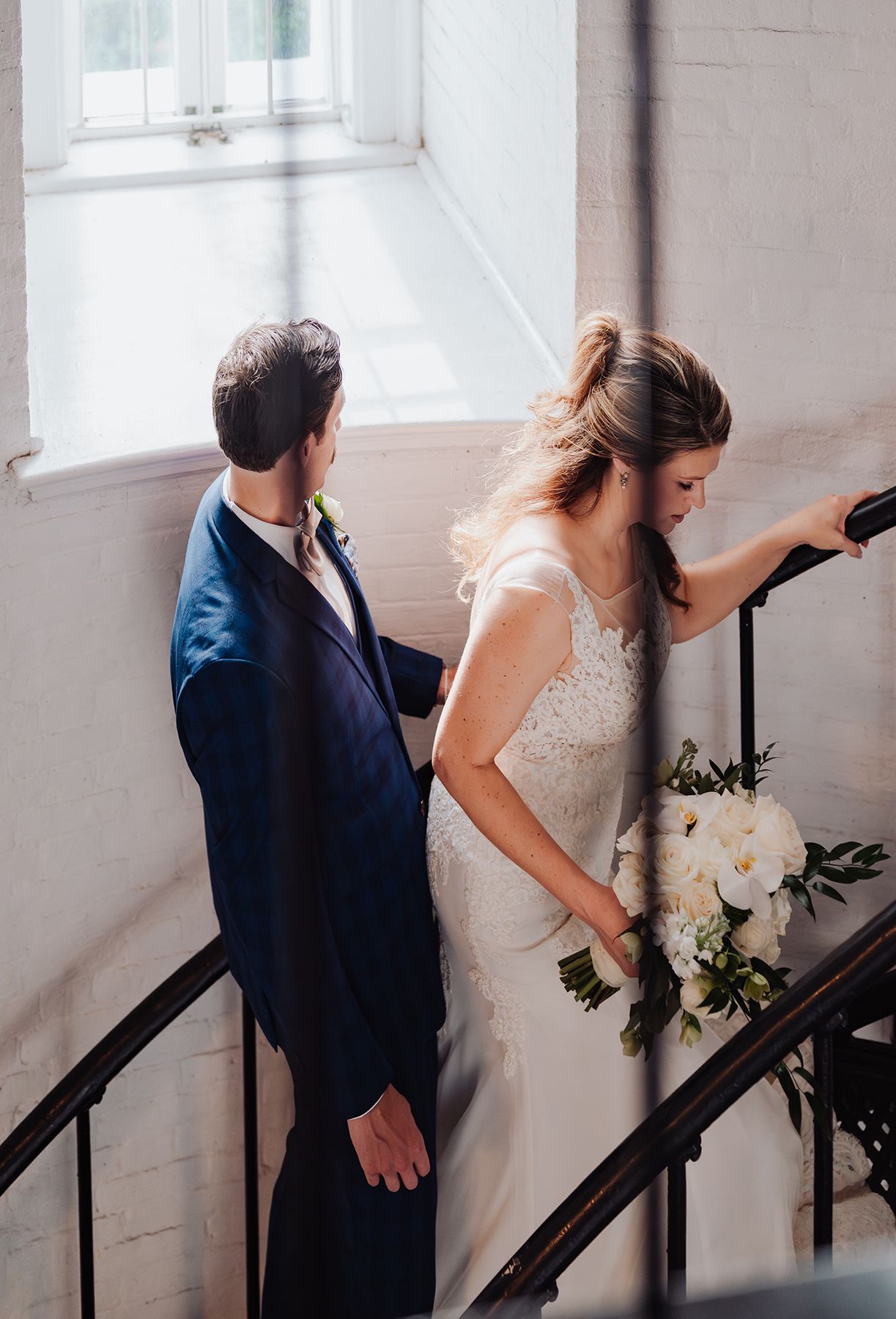 A couple in wedding attire ascend a staircase in sequence, creating a cinematic motion effect in a bright interior.