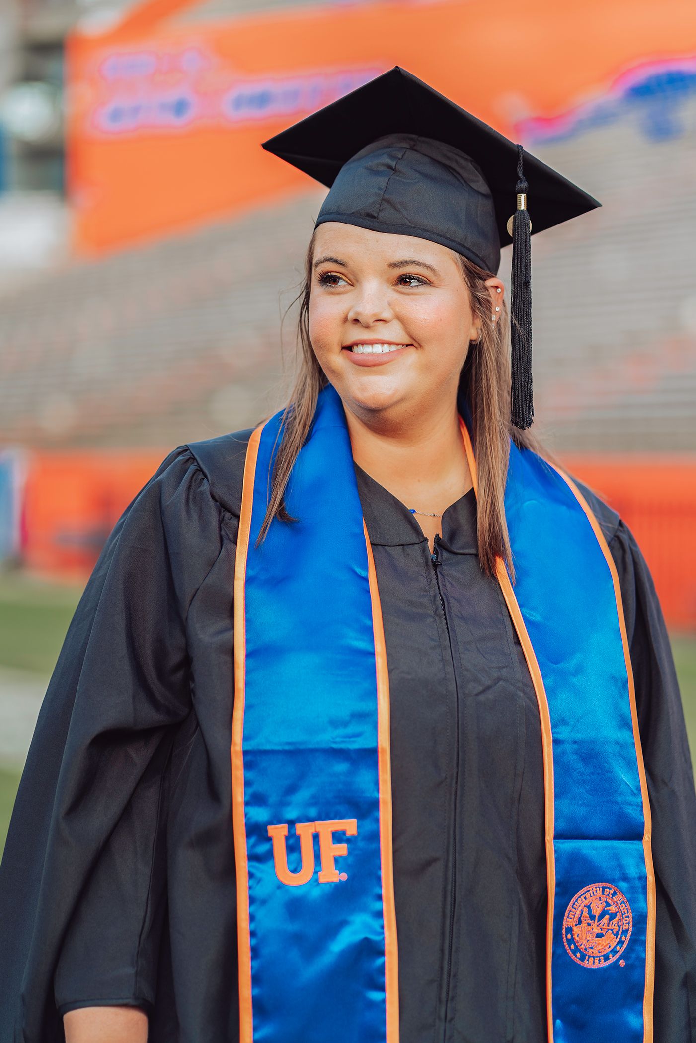 Graduate wearing traditional cap and gown with blue and orange University of Florida stole at commencement ceremony in Gainesville, Florida