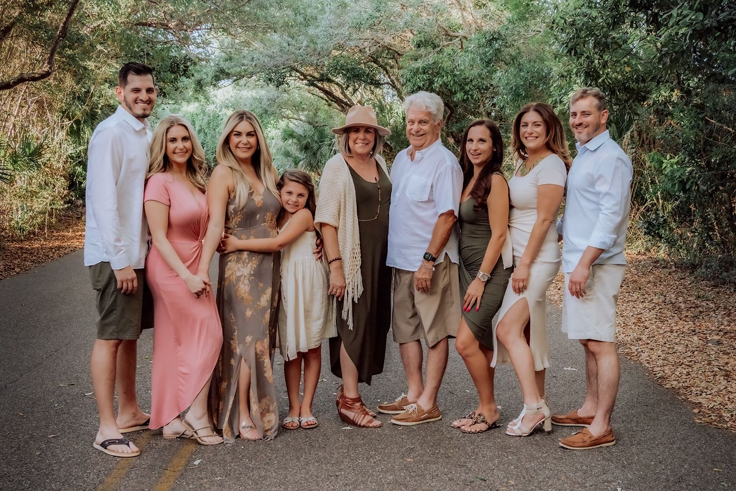 A group in coordinating pink and neutral outfits poses for photos in an outdoor garden setting for family photographer in Jacksonville