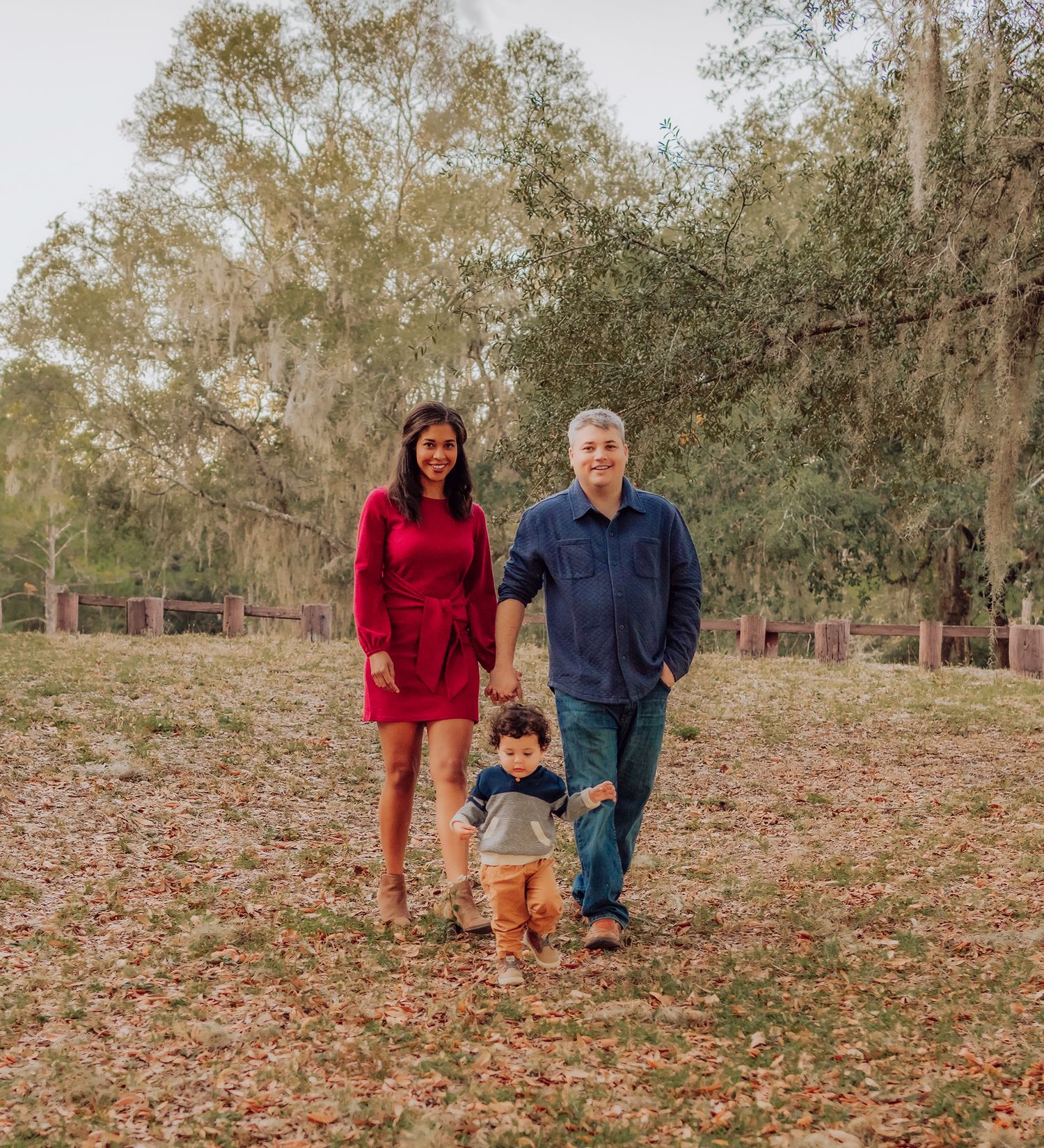 Family walking together through a park filled with fallen autumn leaves on a crisp fall day in Gainesville Florida