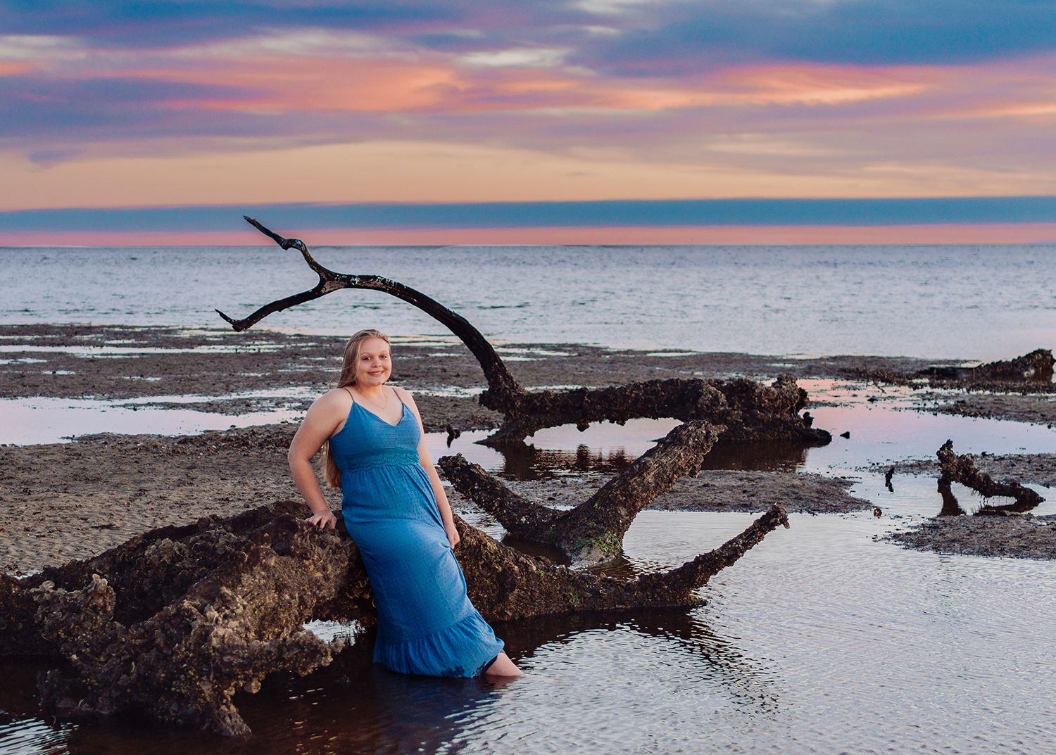 A serene beach scene at sunset with driftwood and tidal pools along the shoreline for high school senior photos in Shired Island, Florida.