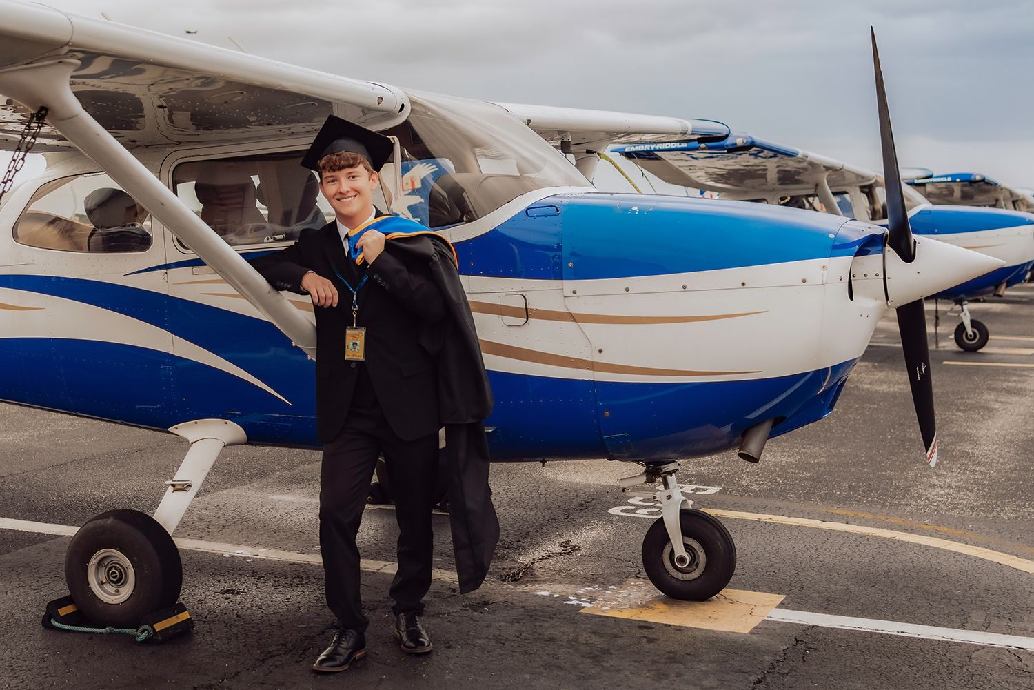 High school senior poses in front of plane for graduation photos at Embry Riddle in Daytona Beach, Florida.
