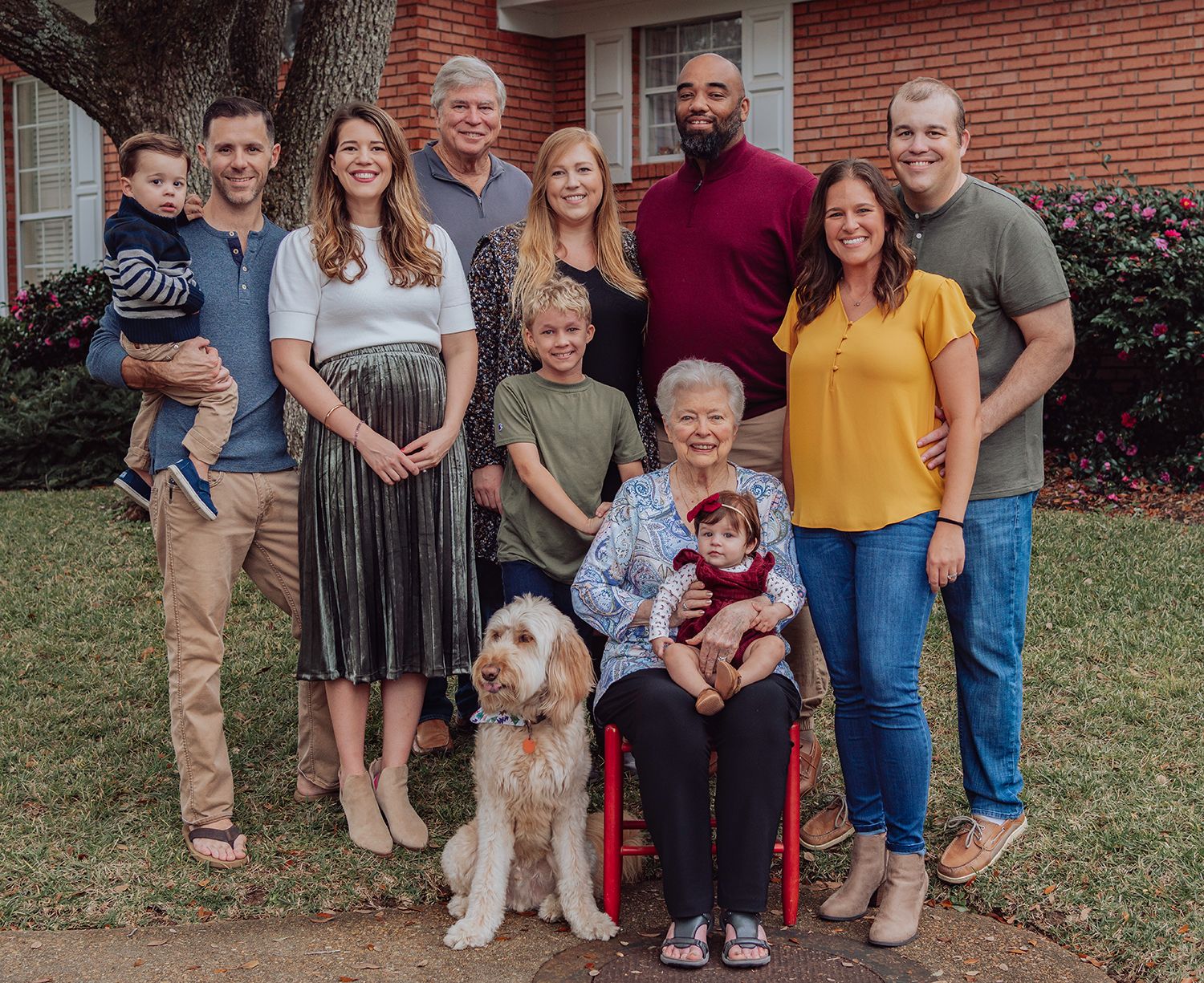 Multi-generational family portrait with a goldendoodle dog in front of a brick building in Gainesville Florida