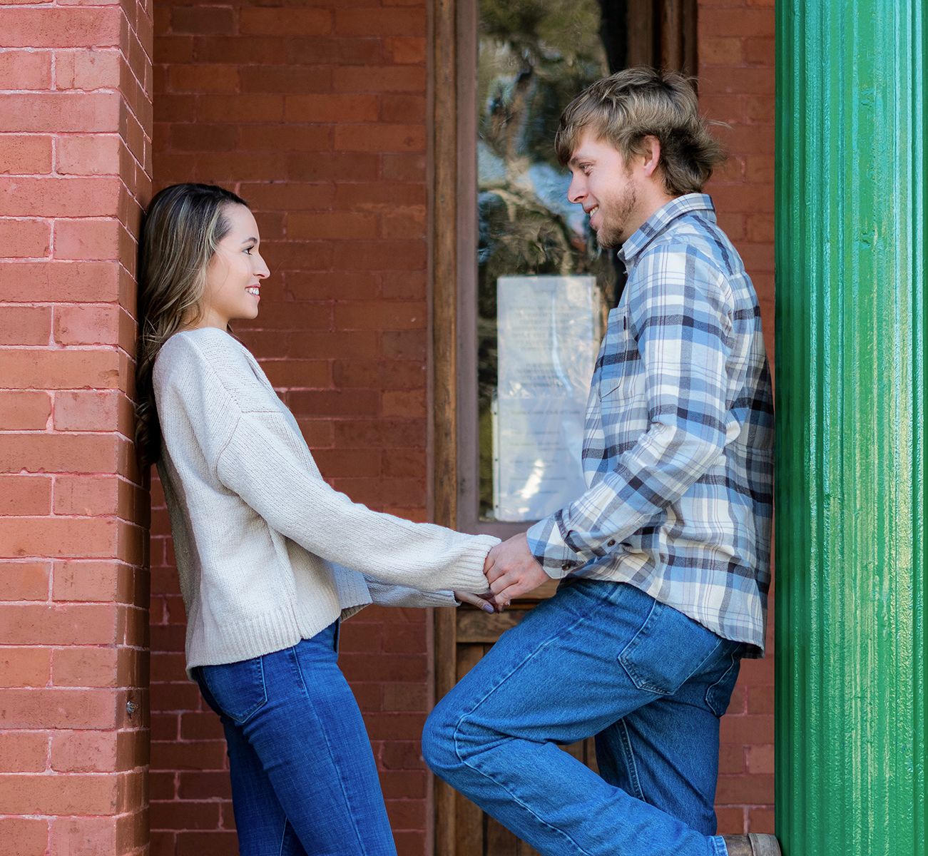 A couple in casual attire dances playfully against a brick wall with turquoise trim in a series of connected photos.