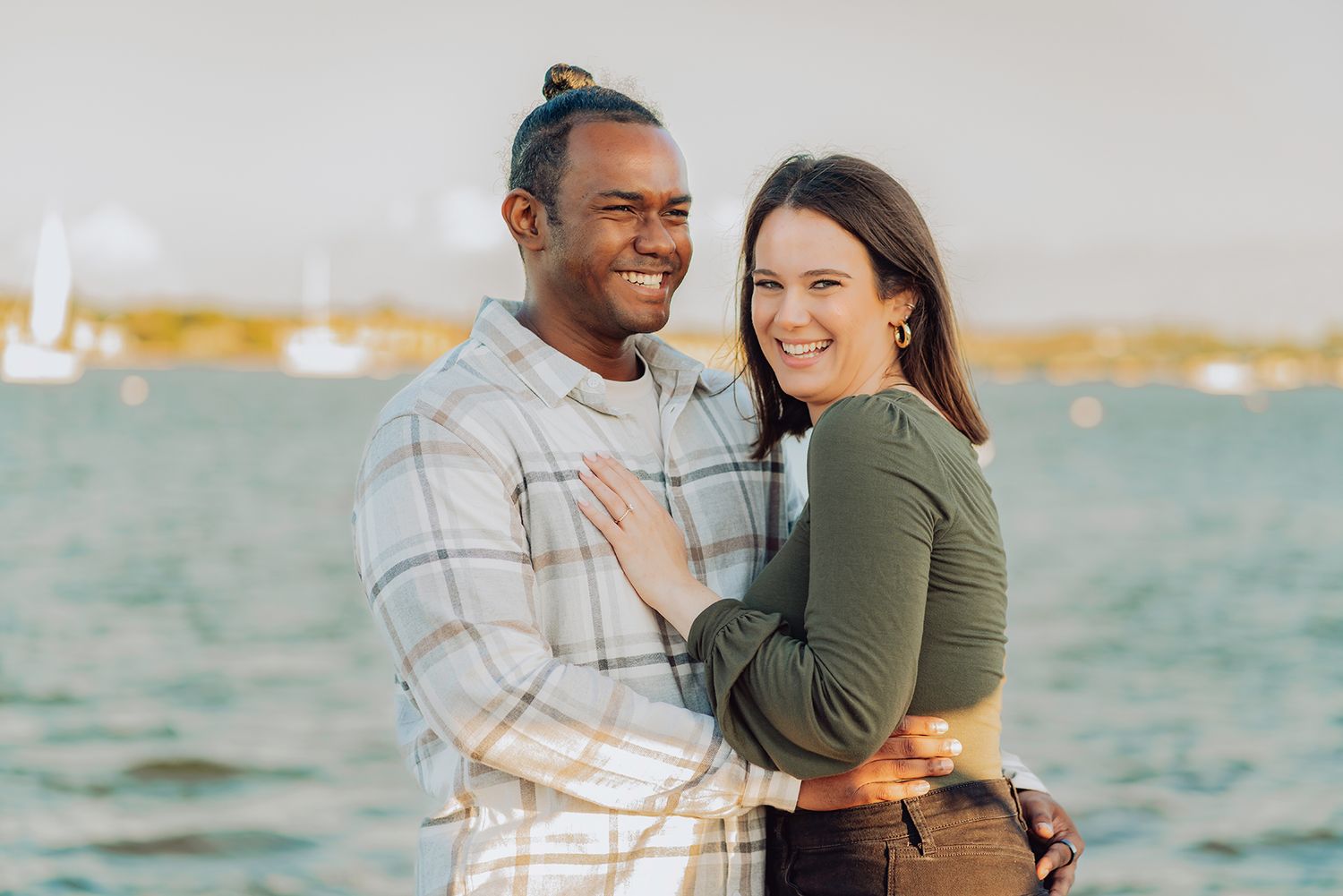 A couple shares a romantic moment together while standing by the ocean during sunset.