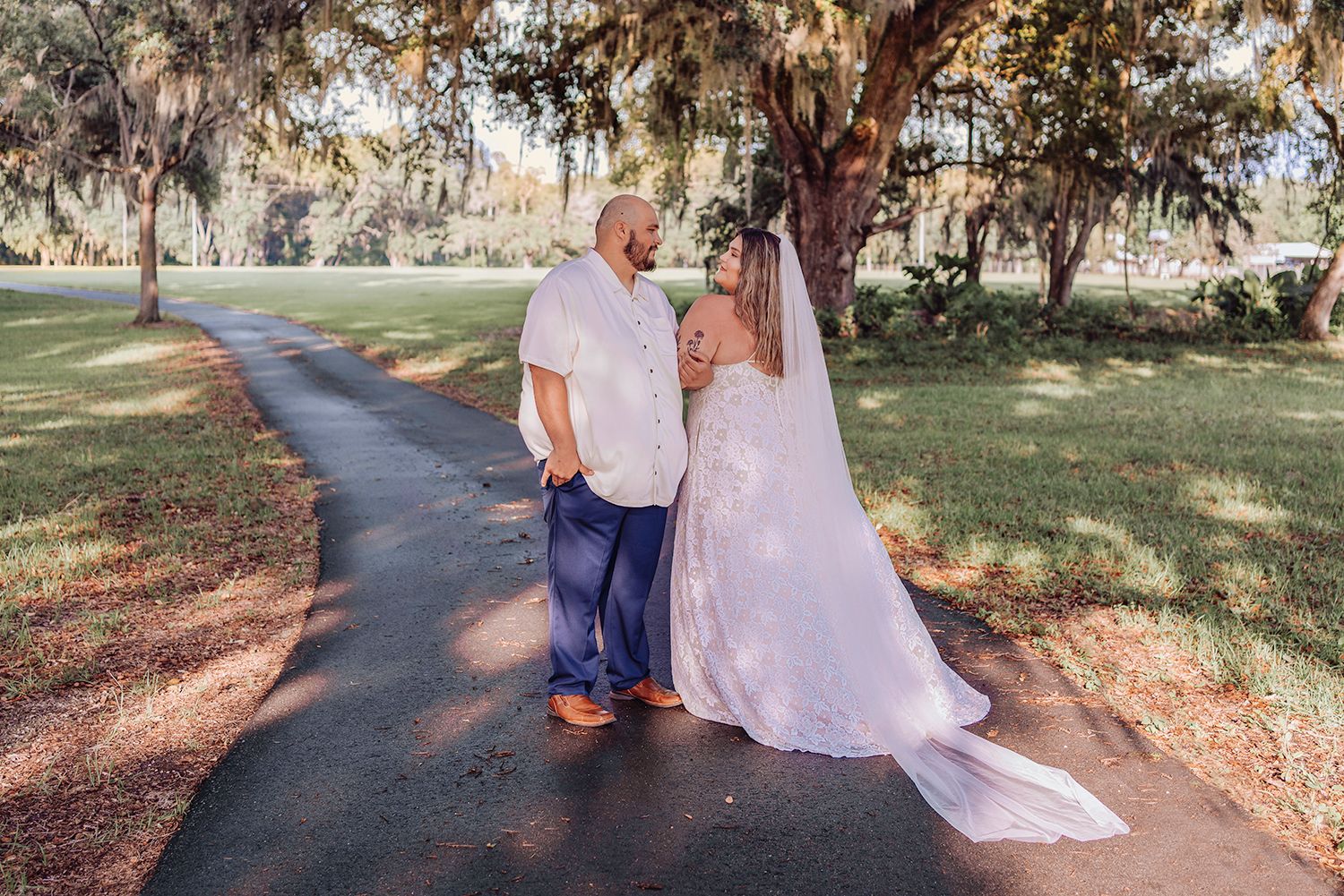 A couple walks along a winding path through a scenic park setting during a wedding photo session.