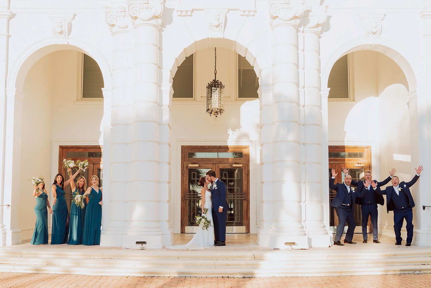A panoramic view of a grand white marble interior hallway with arched columns and visitors exploring the space.