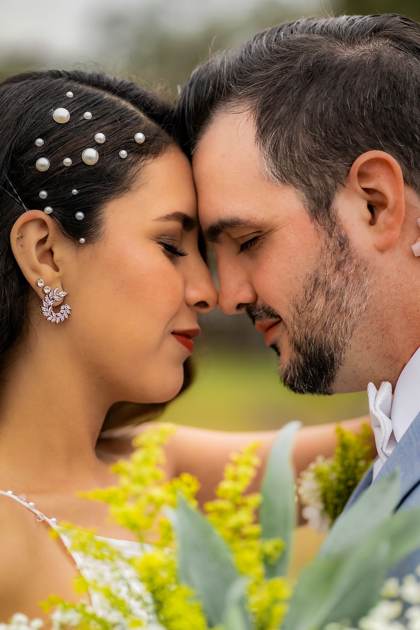 Close up romantic wedding photo with pearl hair accessories and yellow flowers in soft outdoor lighting.