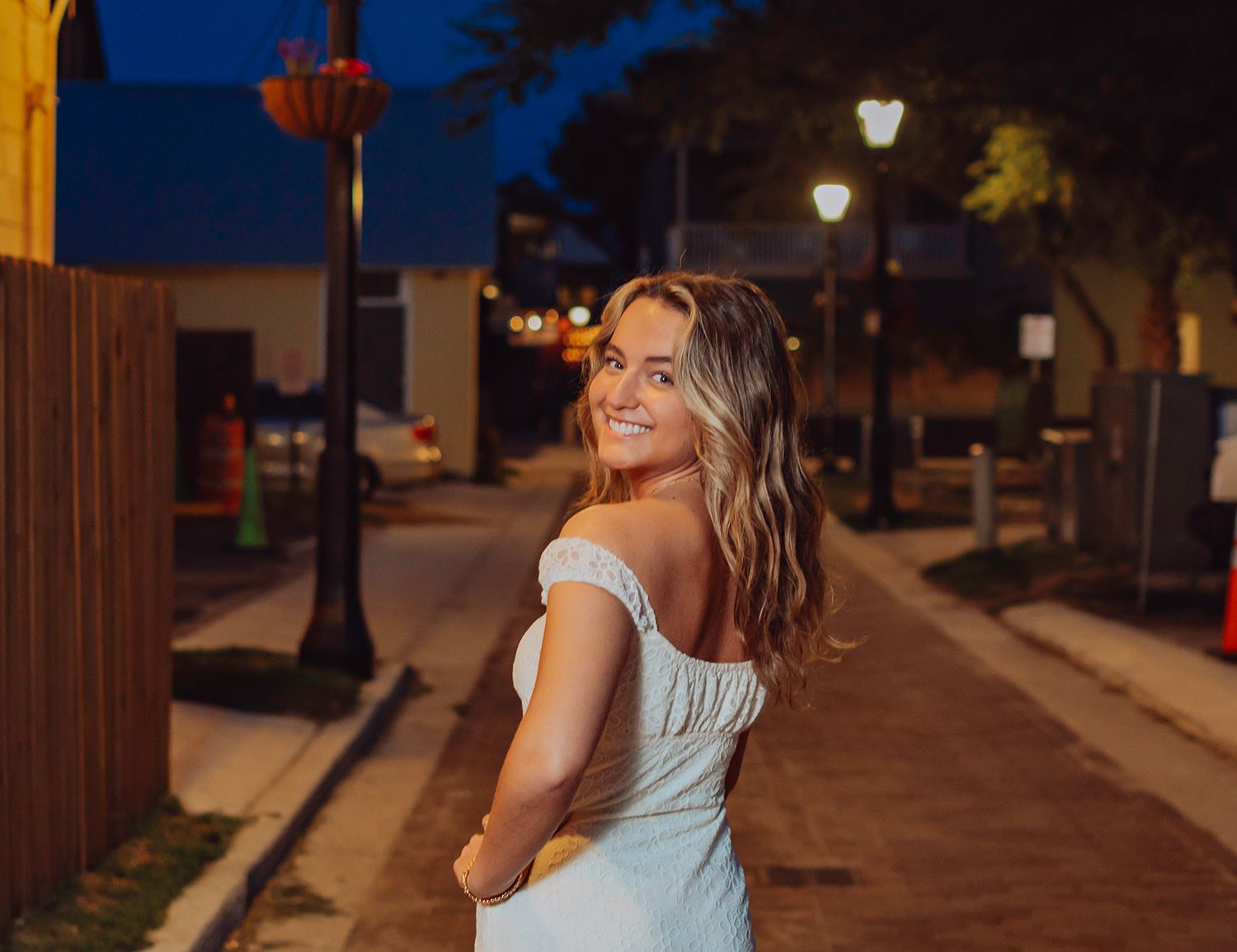 High school Senior a white dress smiles over their shoulder for graduation photos in St. Augustine, Florida