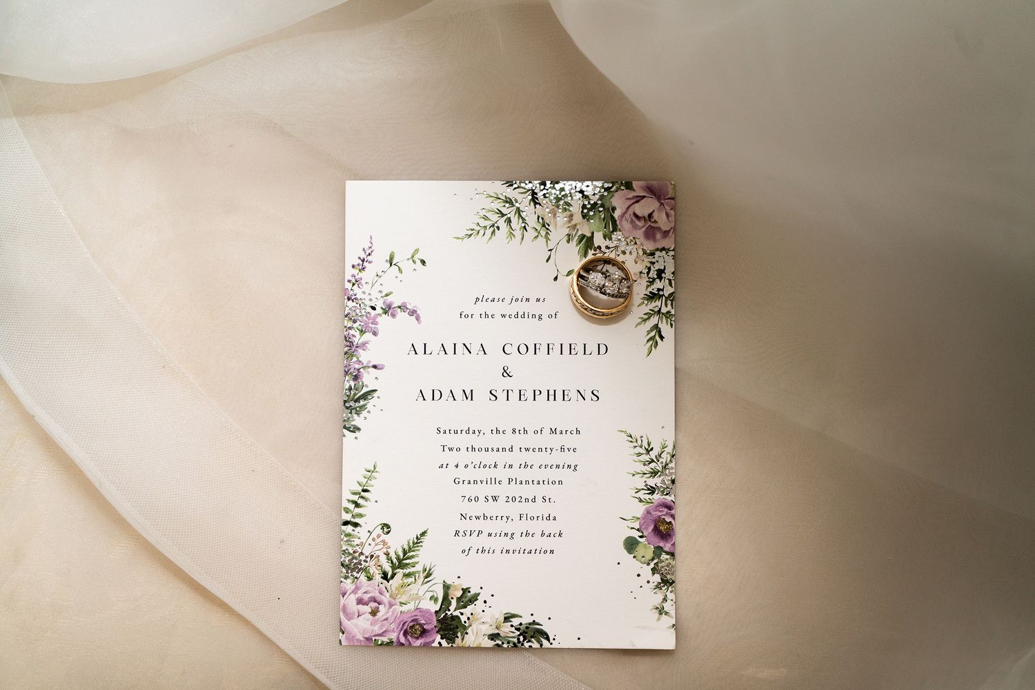 Elegant wedding invitation with floral design on cream colored fabric.
