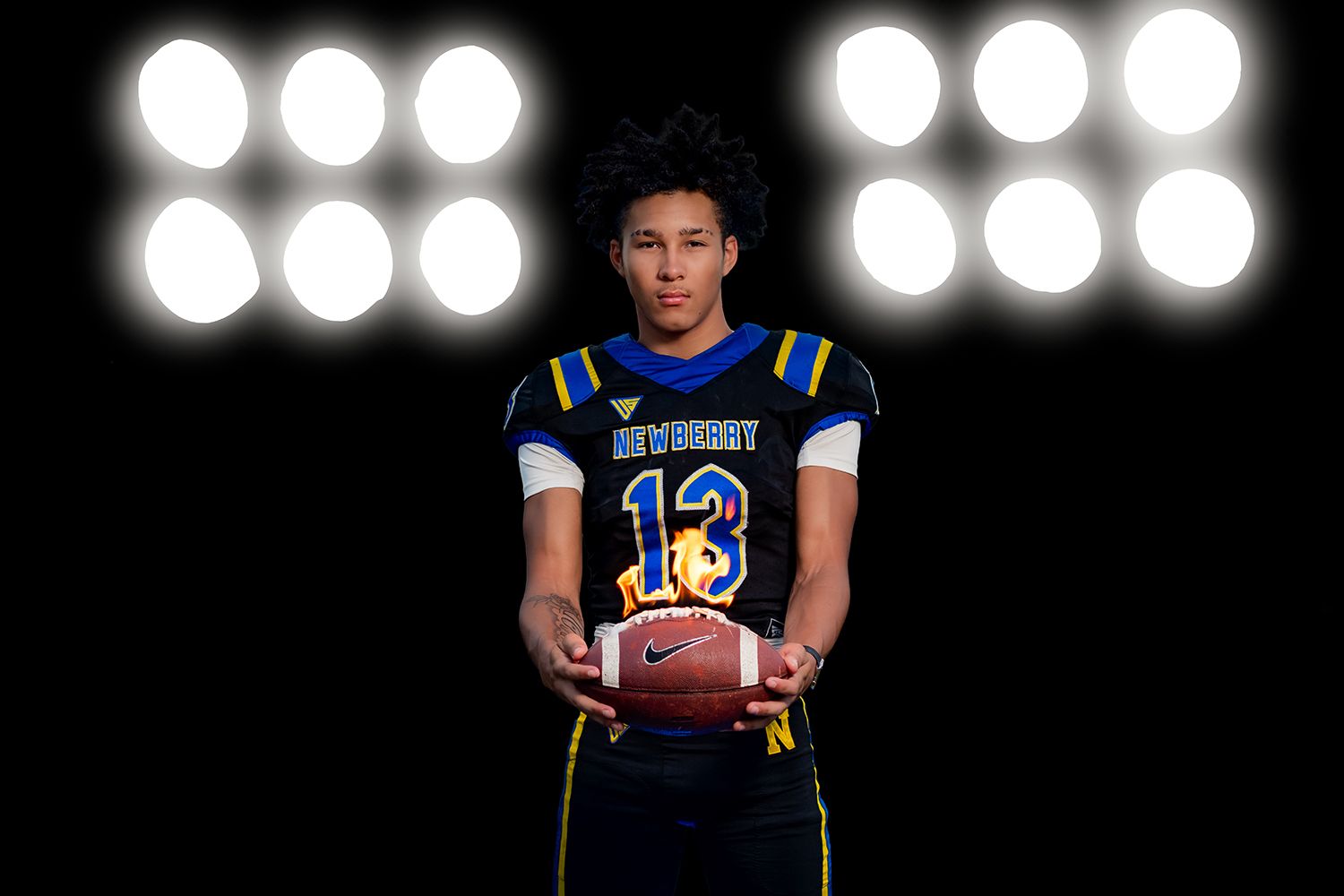 Football player in blue jersey stands against dark background with stadium lights glowing behind them for Newberry Panthers Football